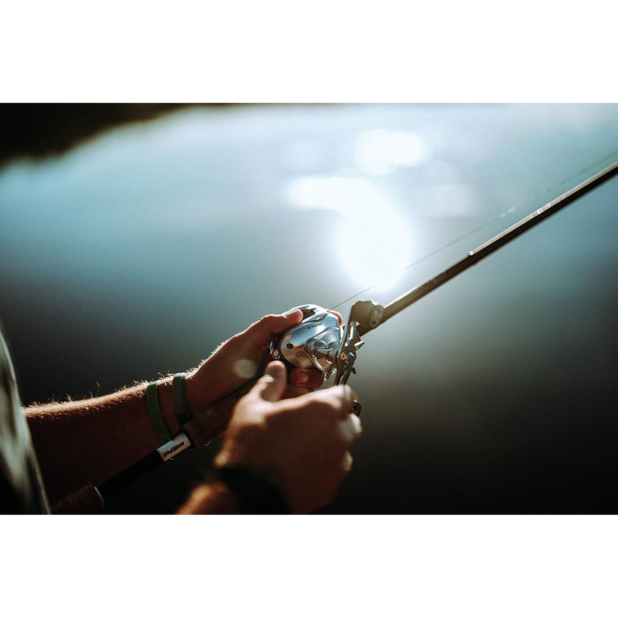Hand holding a fishing rod with a blurred background