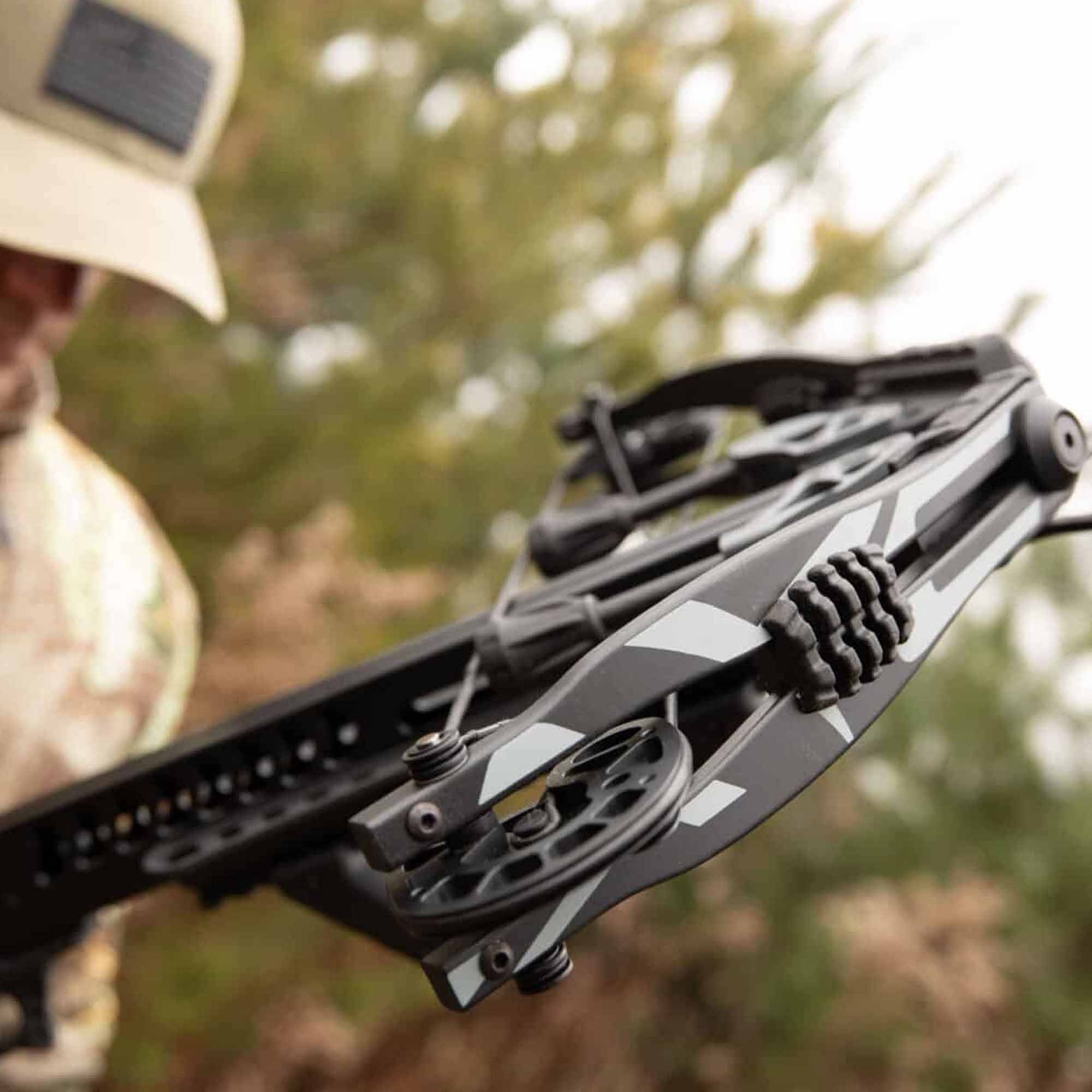 Close-up of a crossbow kit with a blurred background of trees and foliage
