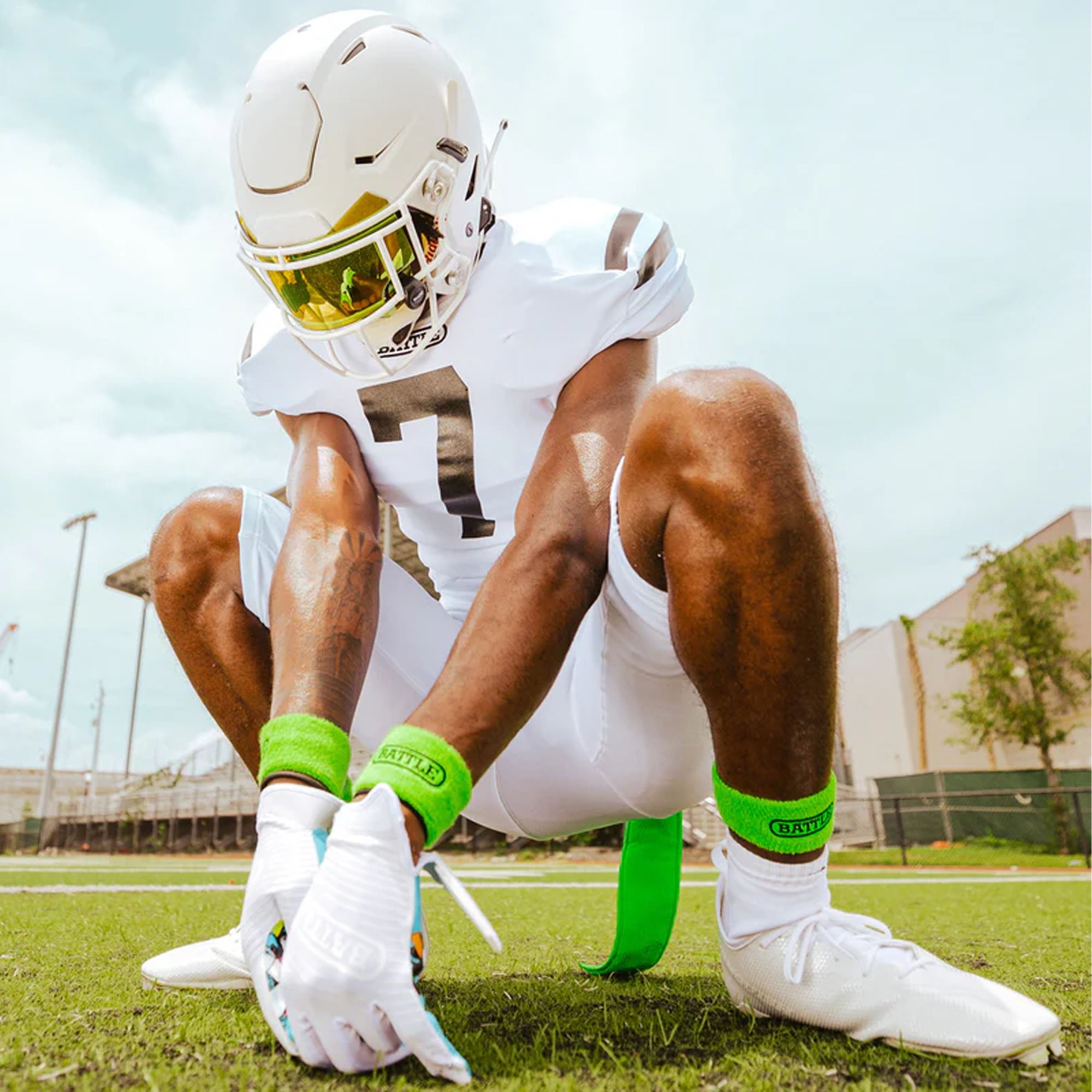 Football player in white uniform with green thick arm bands on a field