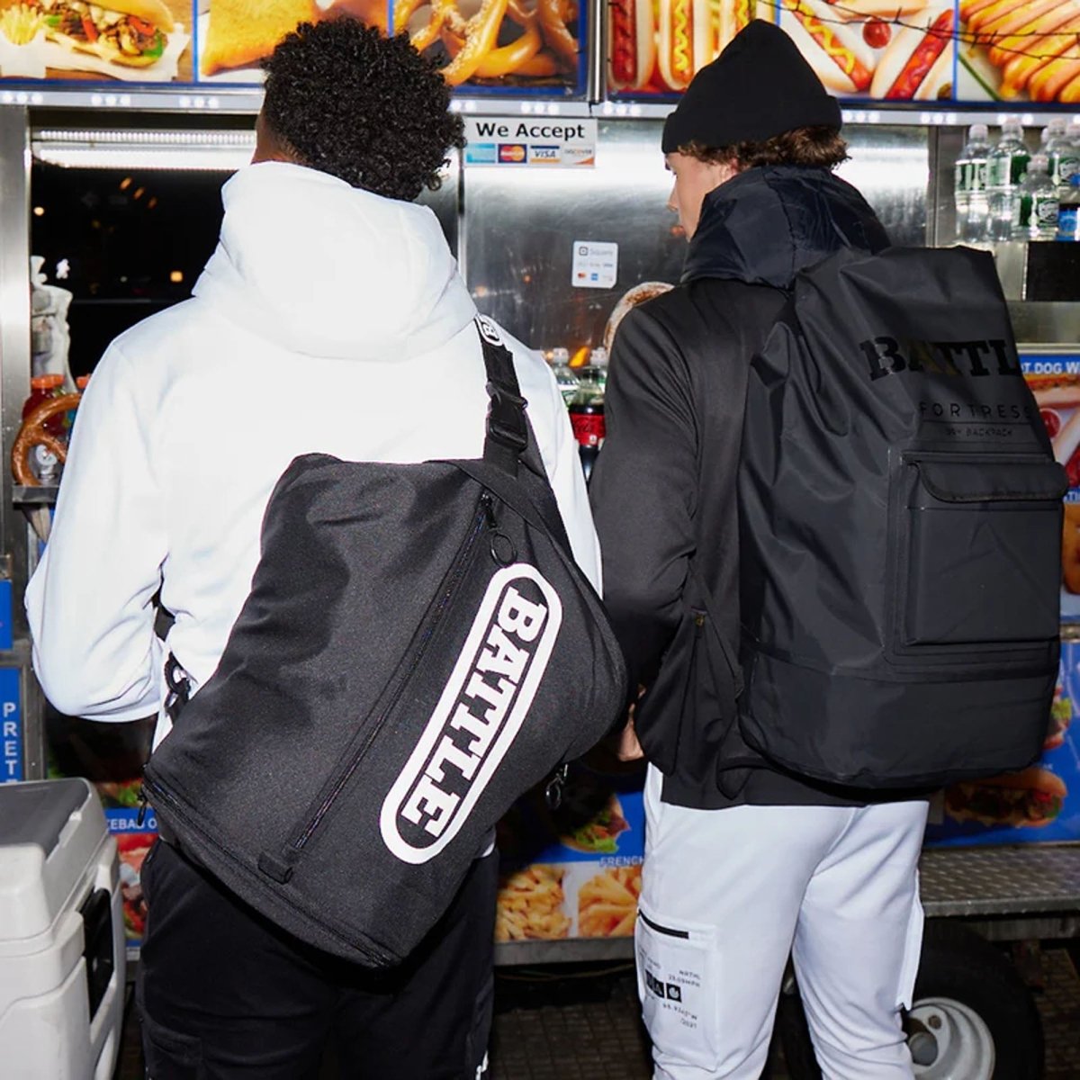 Two people with 'BATTLE' branded sling bag in a fast-food restaurant setting.