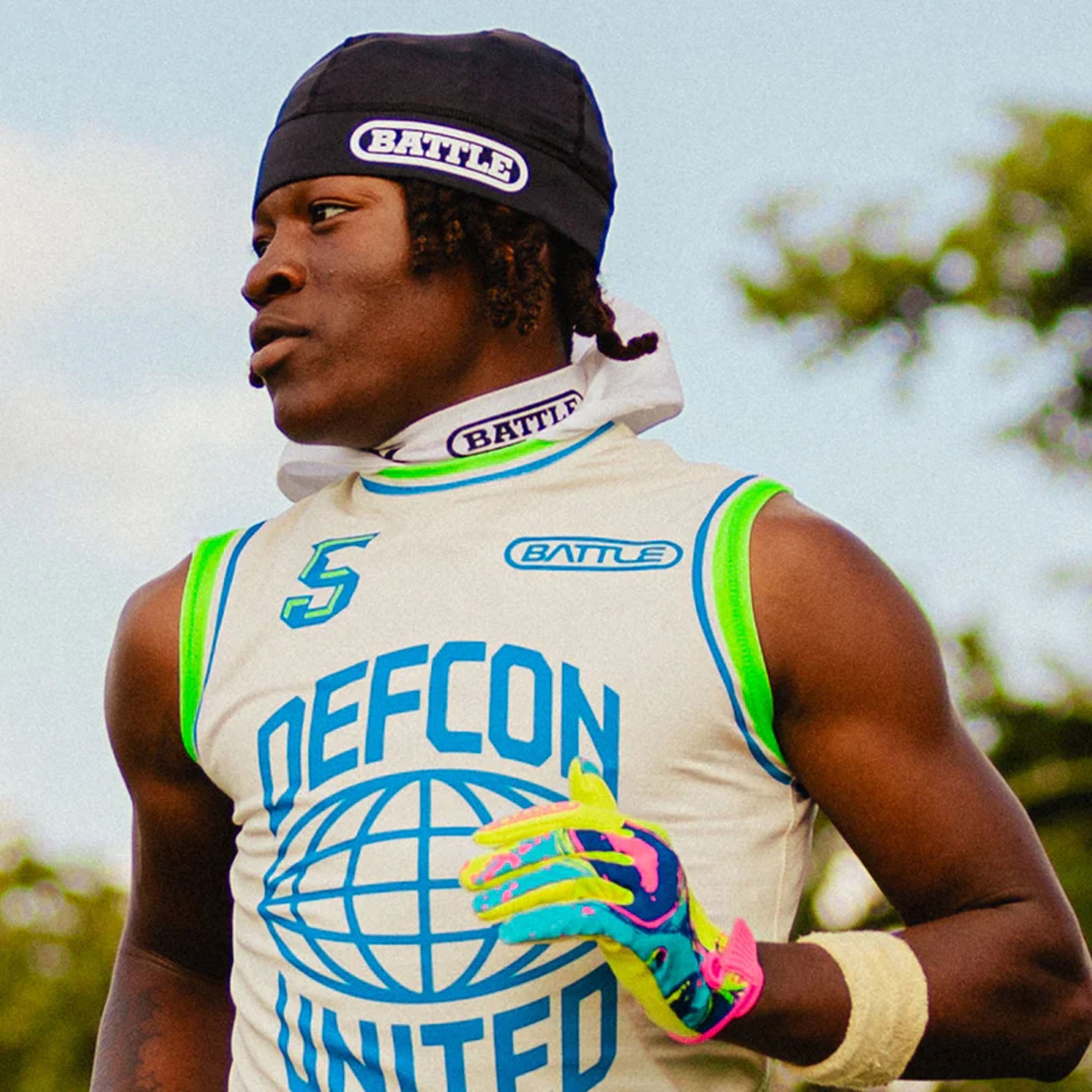 Person wearing a pro skull cap 'DEFCON UNITED' sleeveless shirt with 'BATTLE' branding outdoors