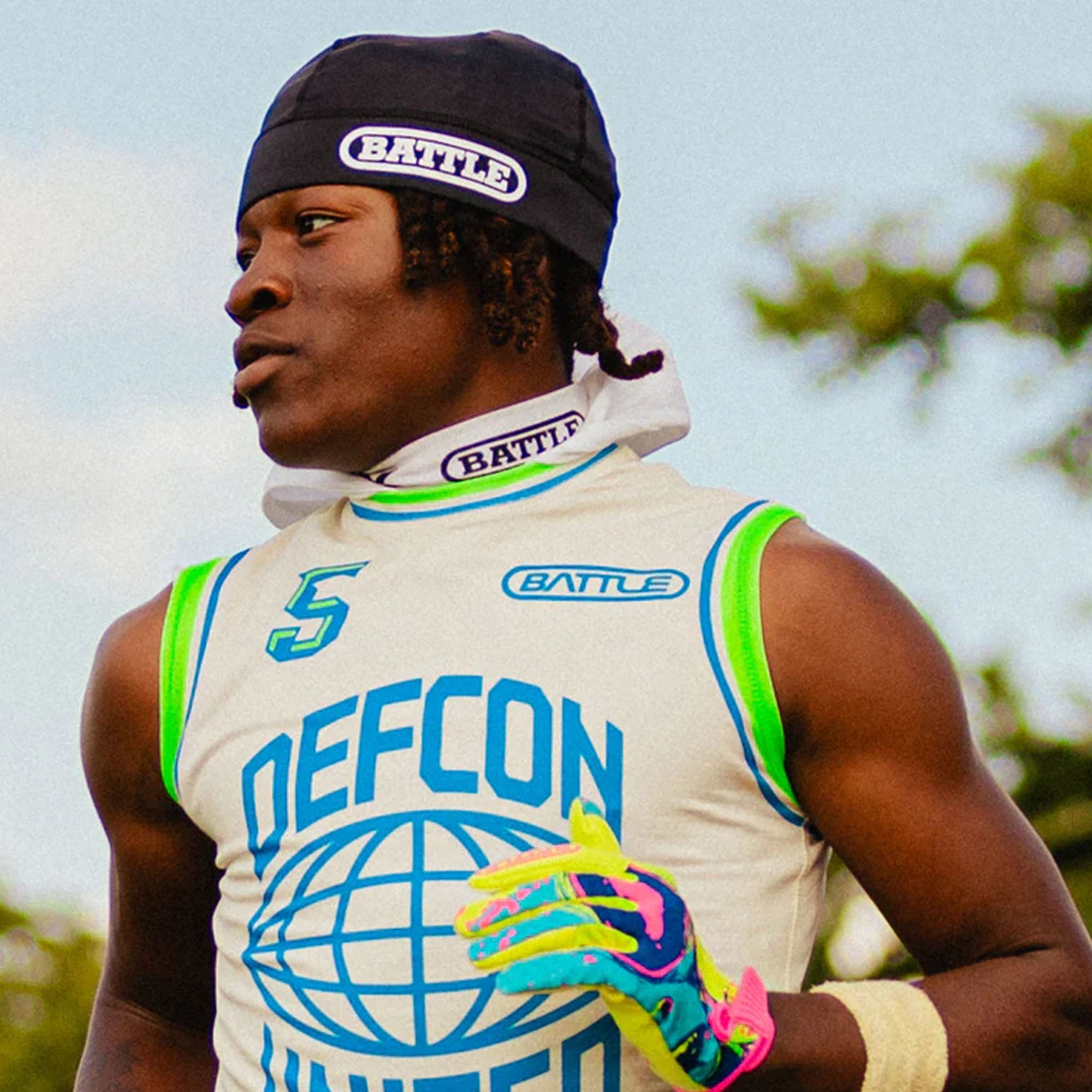 Person wearing a 'Battle' pro skull cap and sleeveless shirt with 'Defcon' branding outdoors.