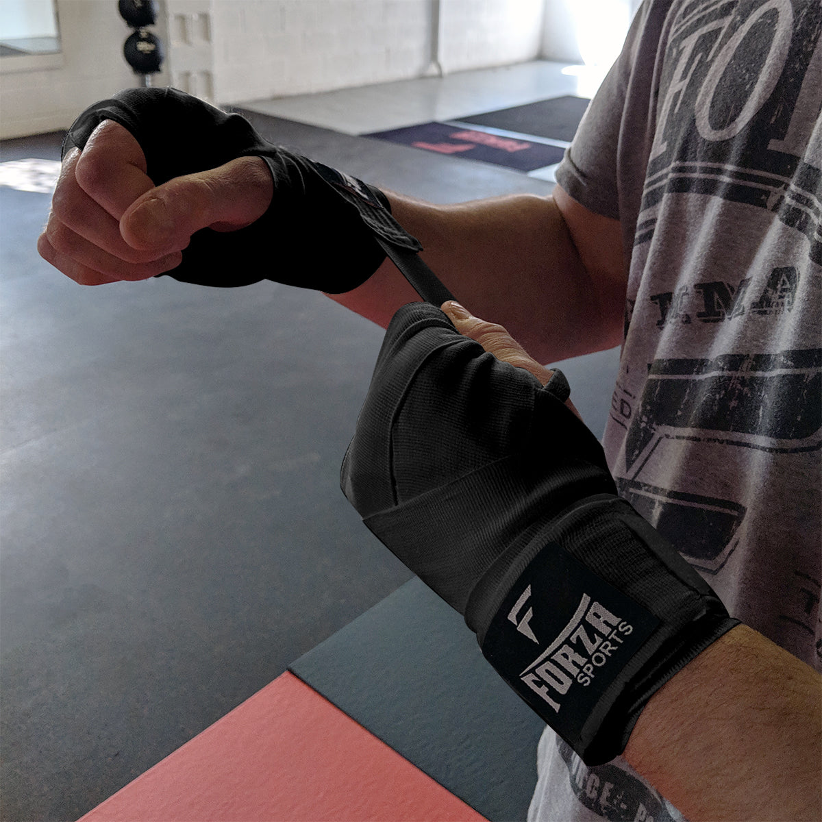 Person wrapping boxing hand wraps on a gym floor