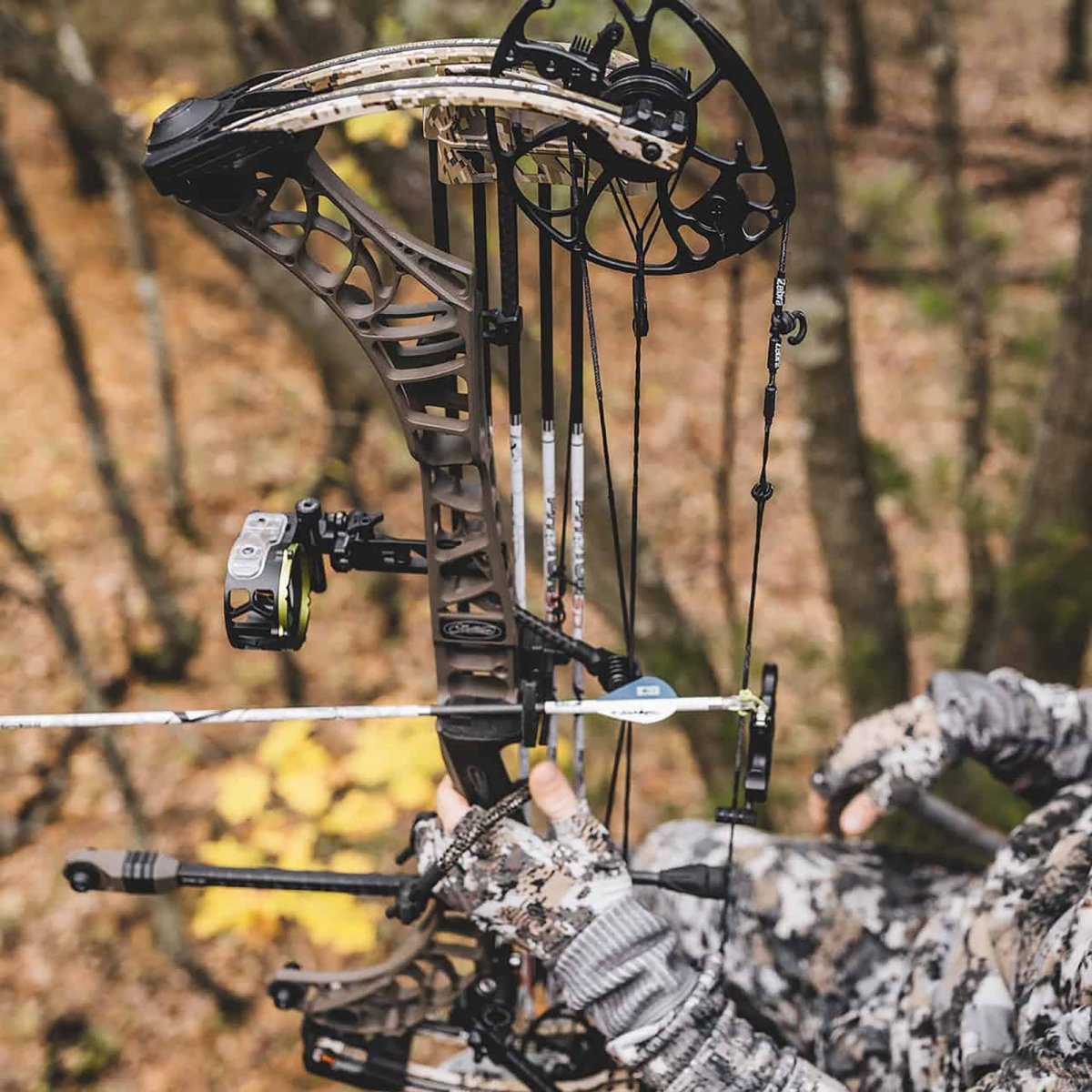 Compound bow brifge lock compatible sights with camouflage glove in a forest setting
