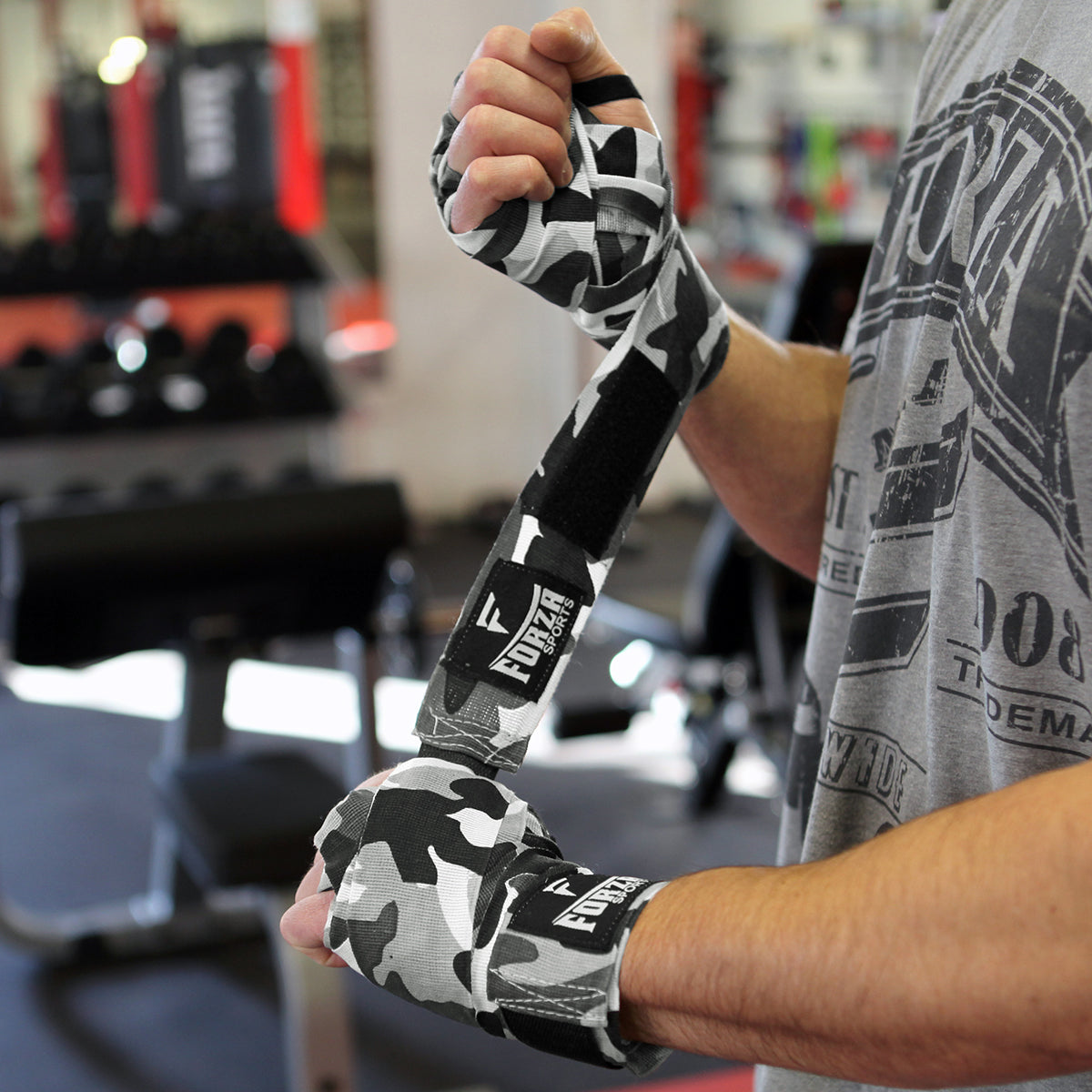 Person wrapping their hands with camouflage boxing tape in a gym setting