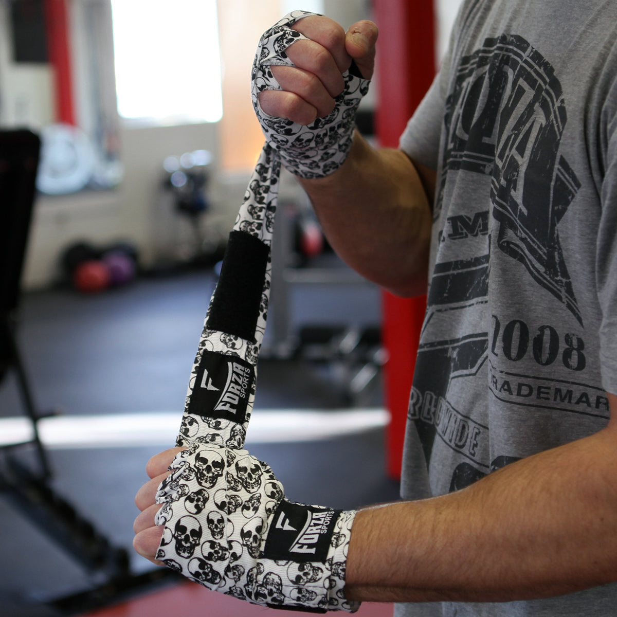 Person wearing boxing bandages with a skull pattern in a gym setting