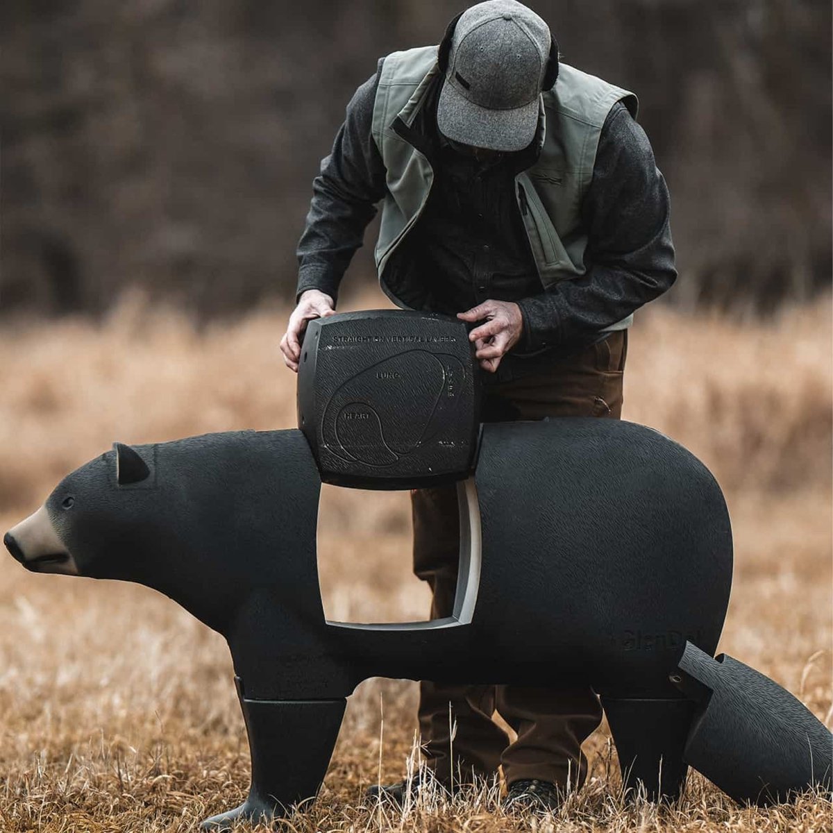 Person holding a 3d bear archery target hunting decoy in a field