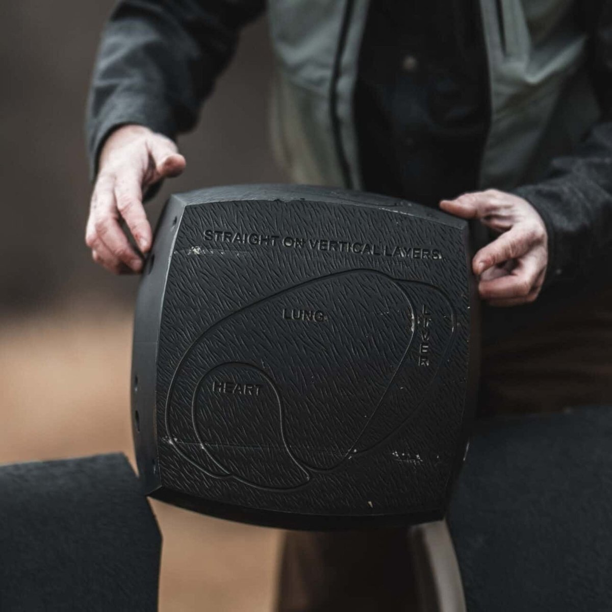 Person holding a black 3d bear archery target weight plate with text on it