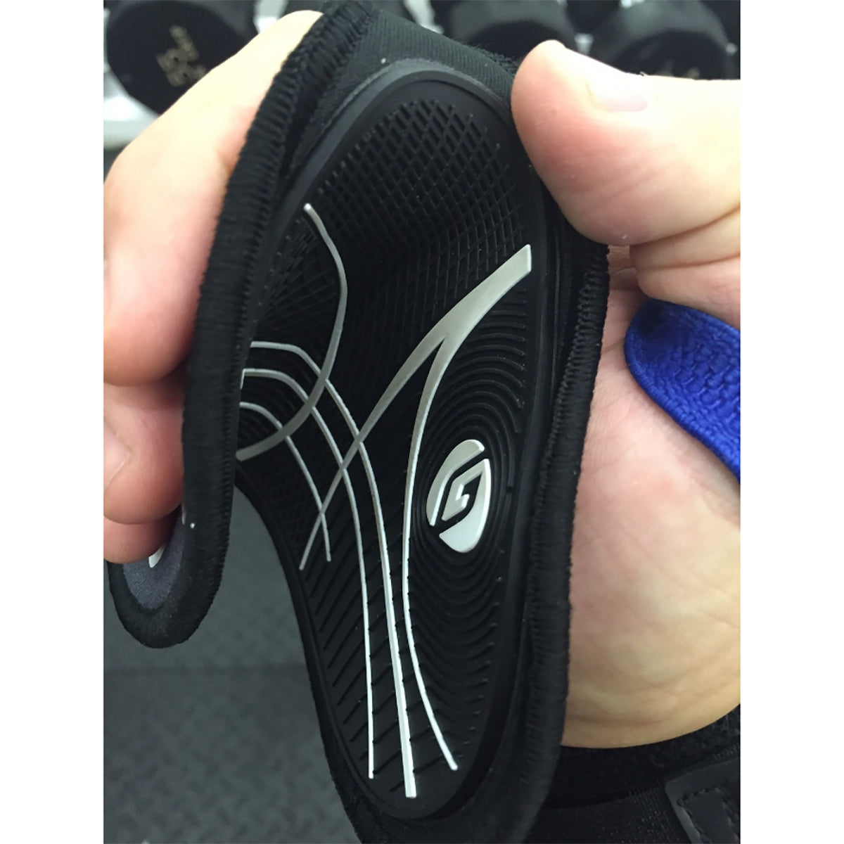 Black athletic shoe sole with brand logo held by a hand