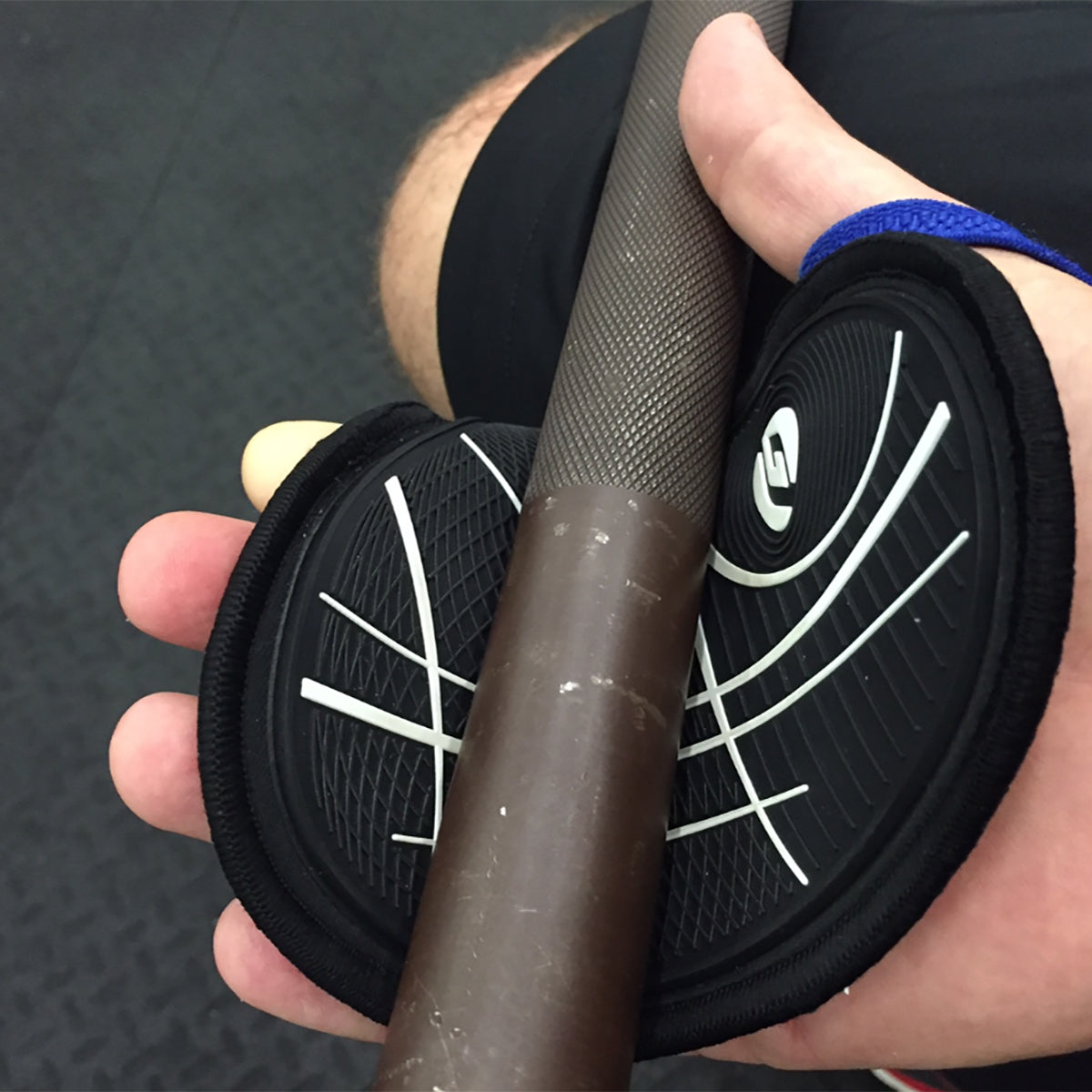 Person holding a black resistance band with white logo on a textured surface