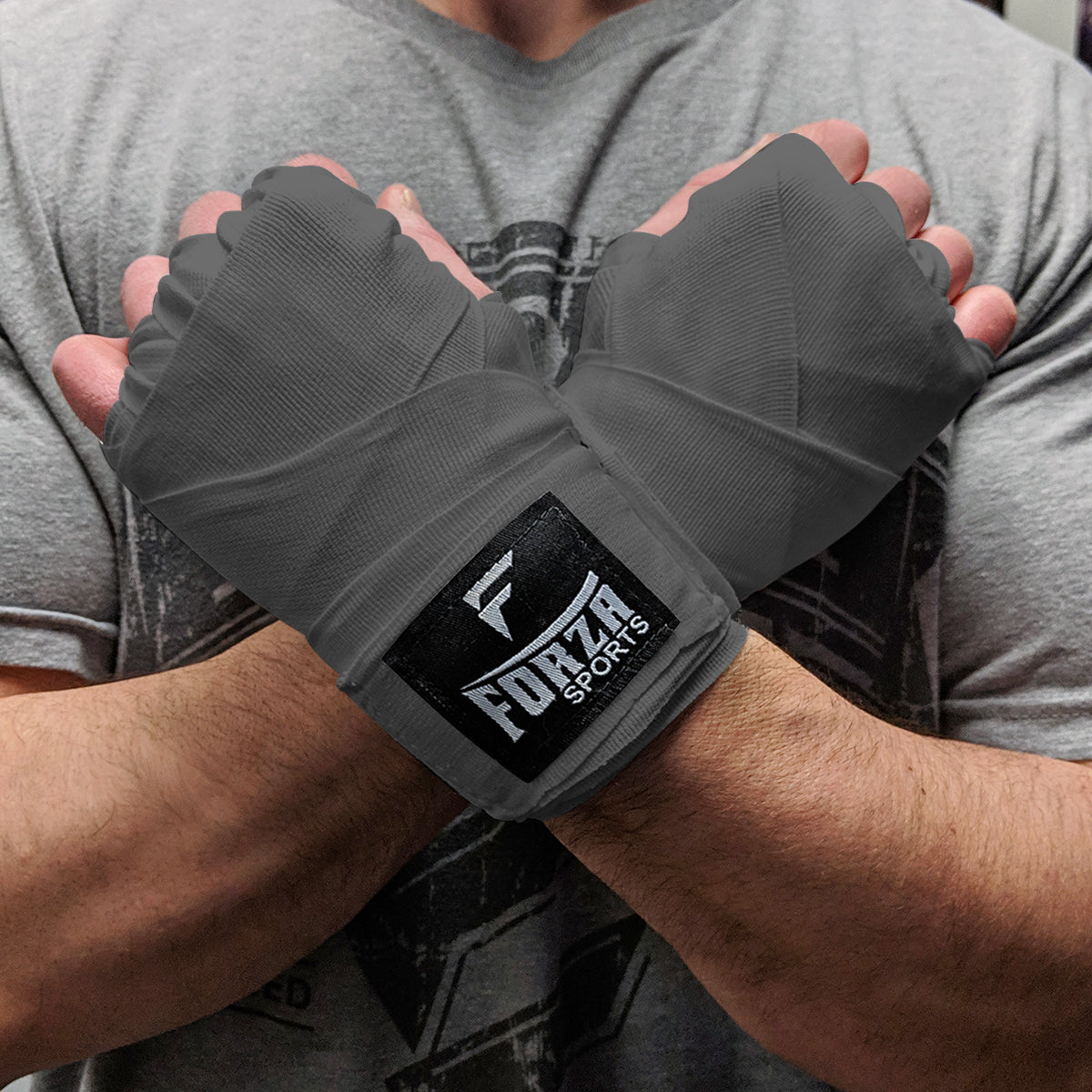 Person wearing gray wrist wraps with Forza Sports logo on a blurred background