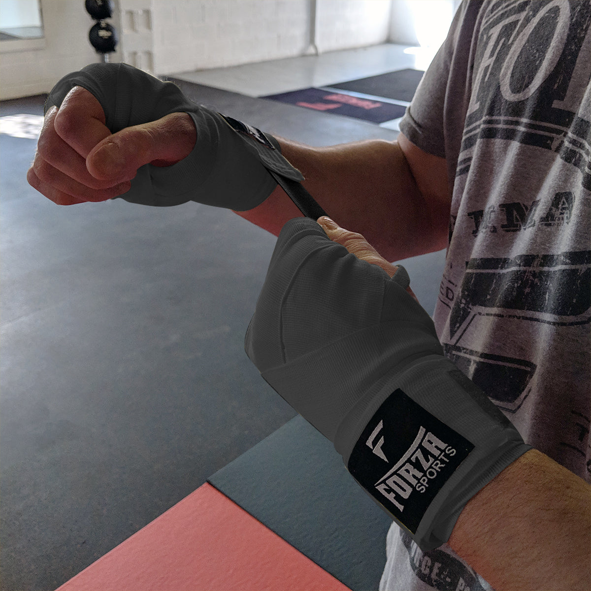 Person wrapping their wrist with Forza Sports wrist wrap in a gym setting