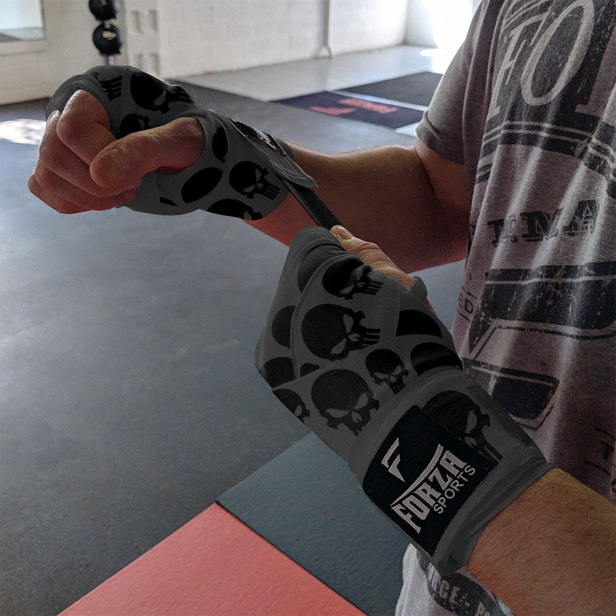 Person wearing black boxing gloves with skull patterns in a gym setting