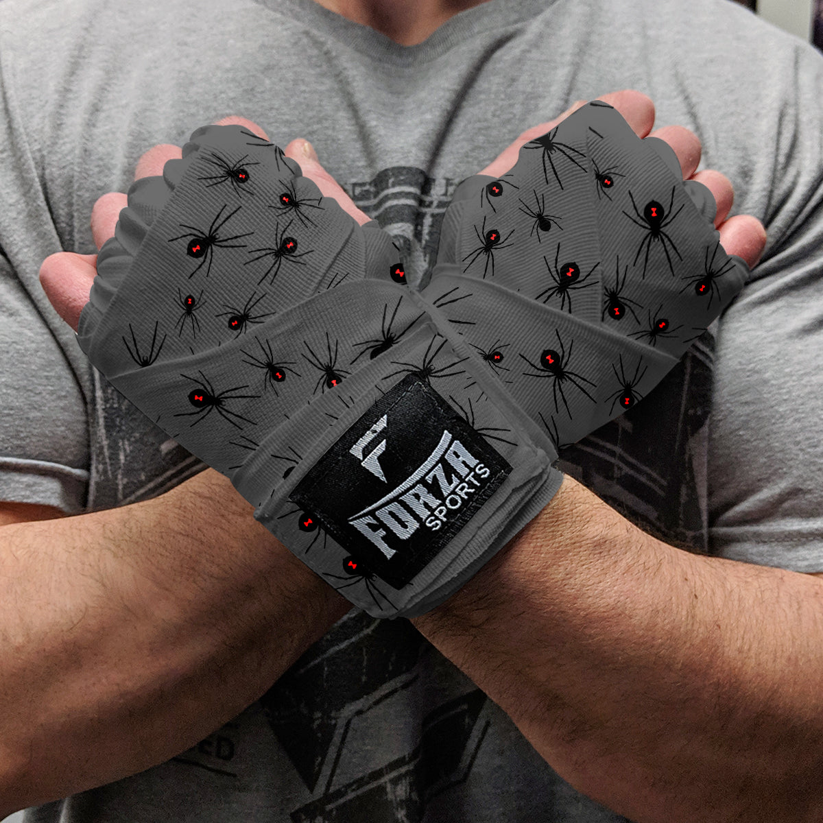 Person wearing gray wrist wraps with black spider design and 'Furza Sports' logo.