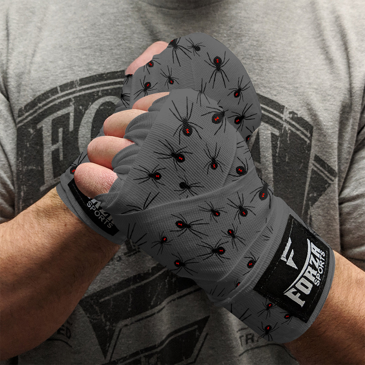 Person holding gray boxing gloves with spider pattern and Fuerza Sports logo.