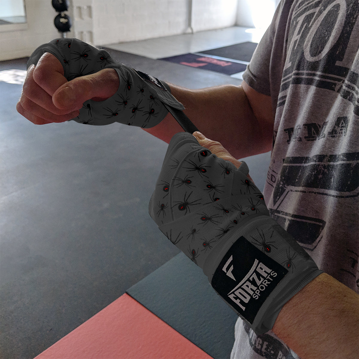 Person wearing boxing gloves with 'Forza Sports' branding in a gym setting