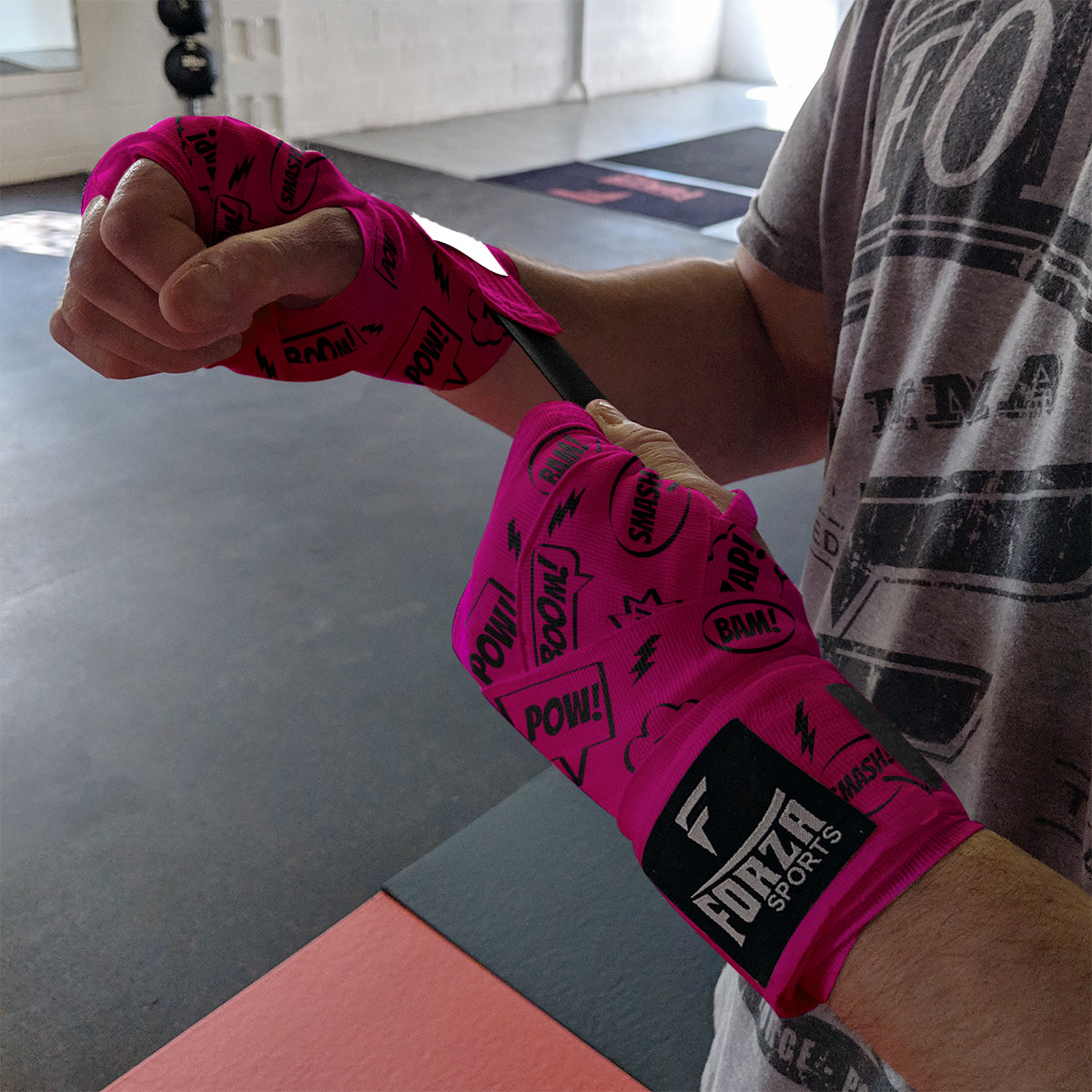 Person wearing pink boxing wraps with 'Forza Sports' branding in a gym setting.