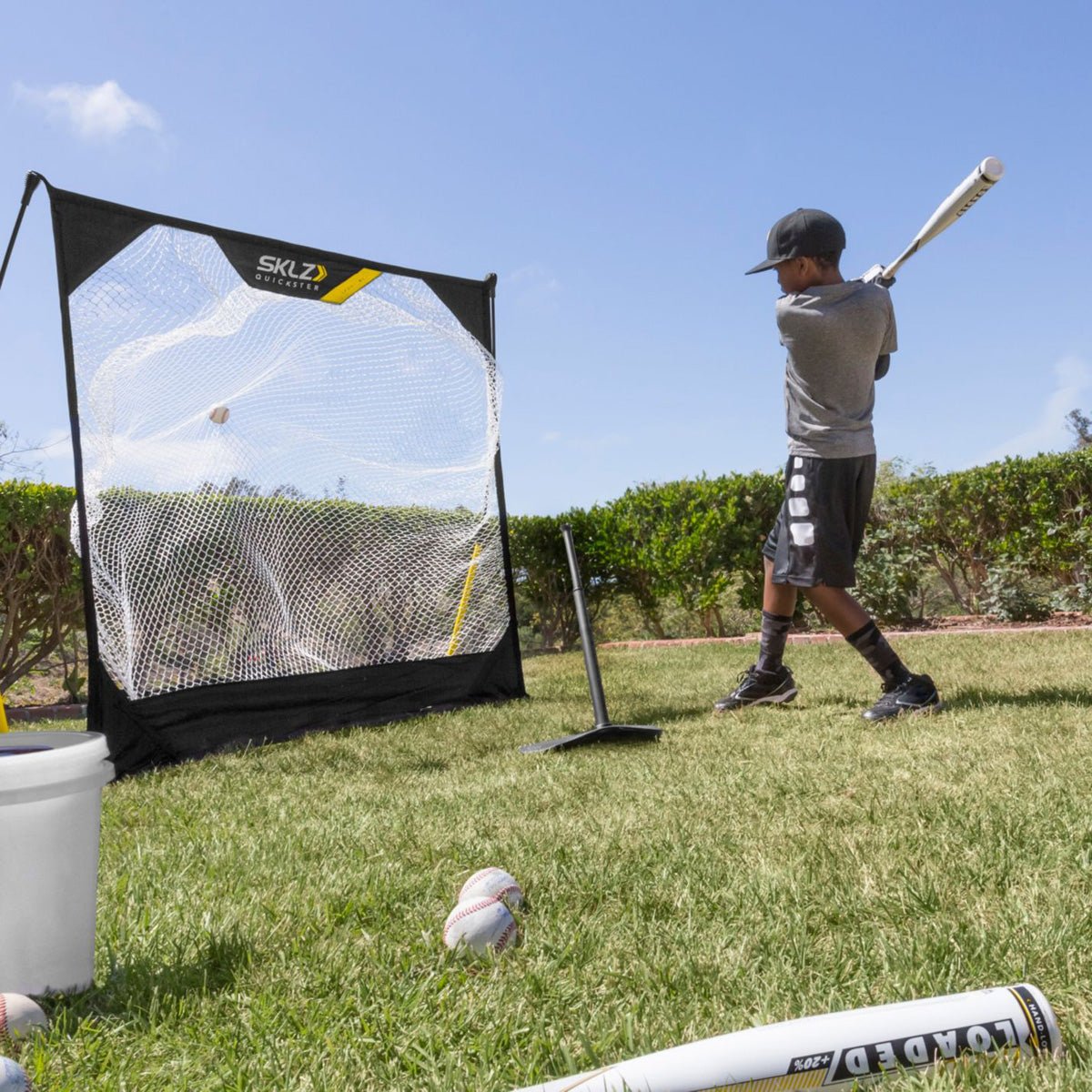 Person practicing batting with baseball training pop in a backyard with a SKLZ pitching net.