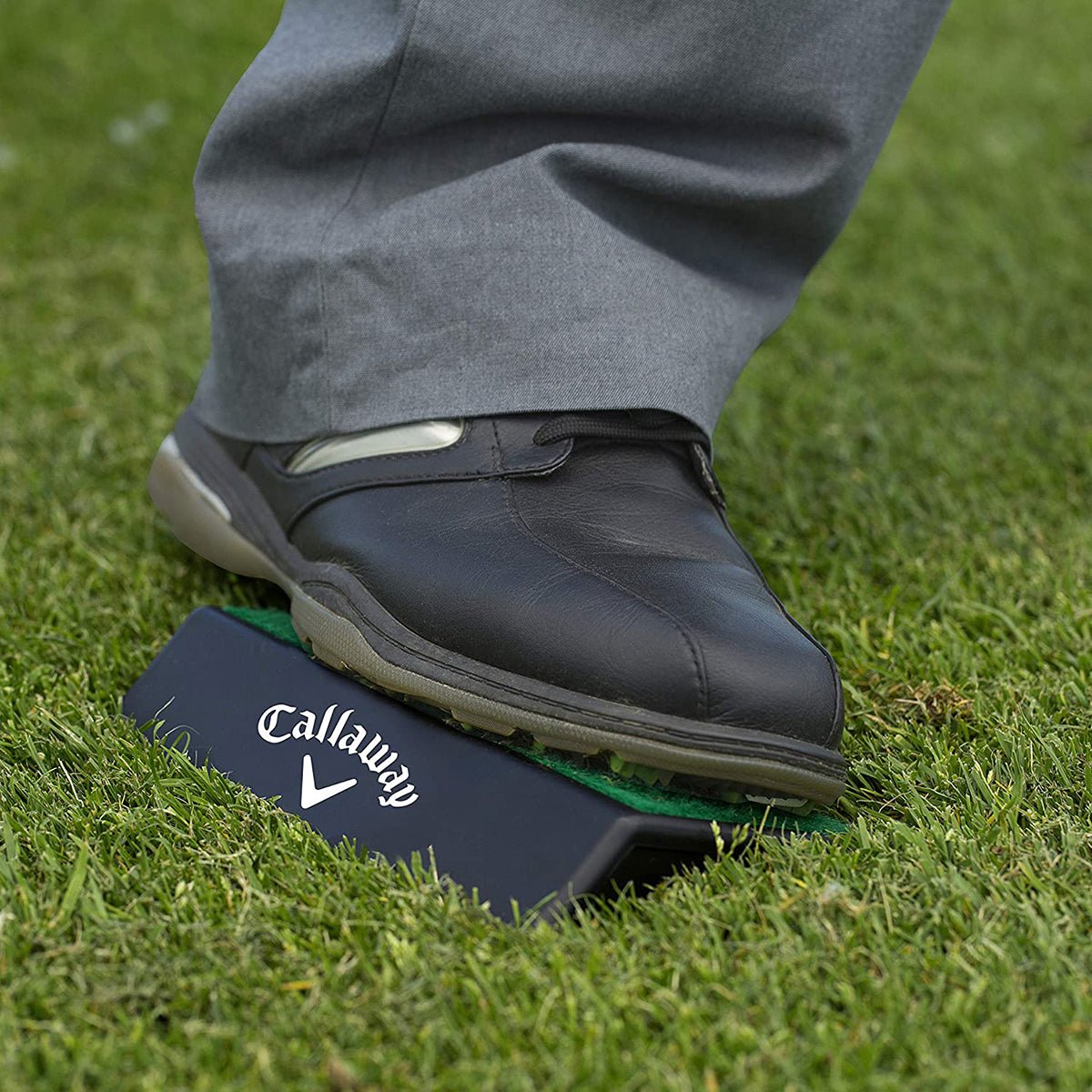 Golf shoe on a Callaway branded golf platform on grass