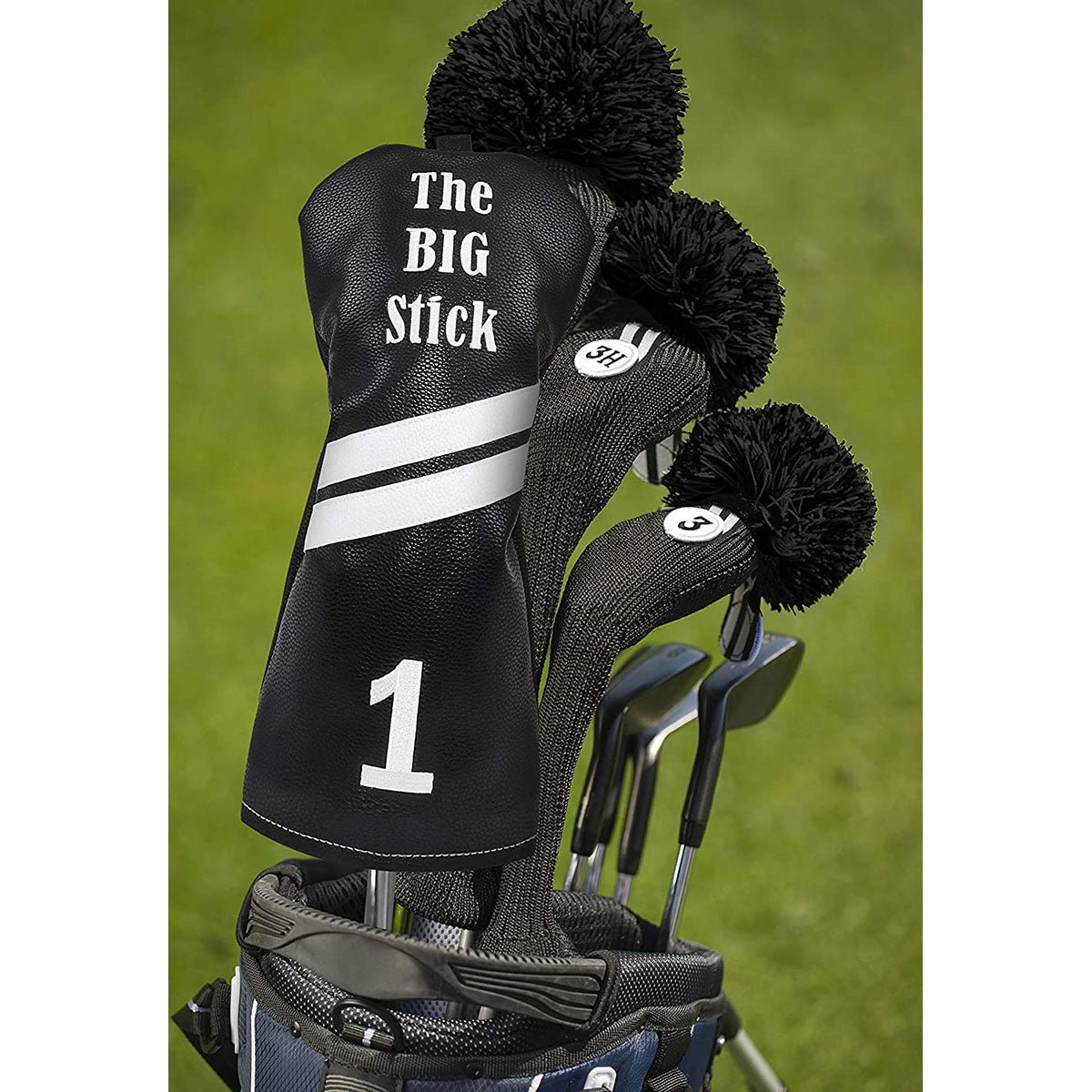 Golf club set with a black leather driver headcover labeled 'The BIG Stick' on a grass background