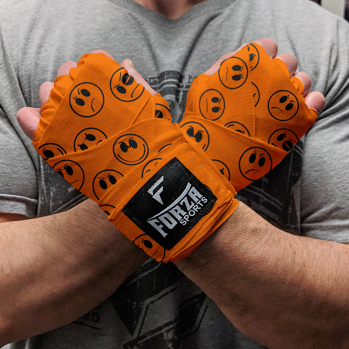 Orange hand wraps with black logos being worn by a person, featuring the Forza Sports brand.