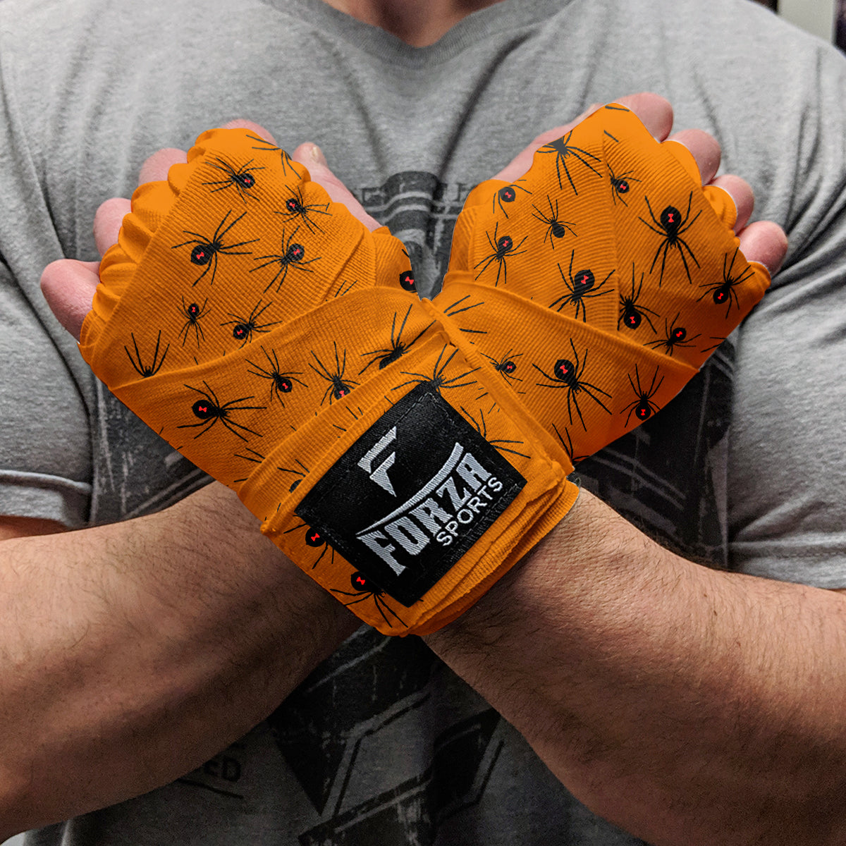 Orange boxing wraps with black spider pattern and Forza Sports logo on wrist