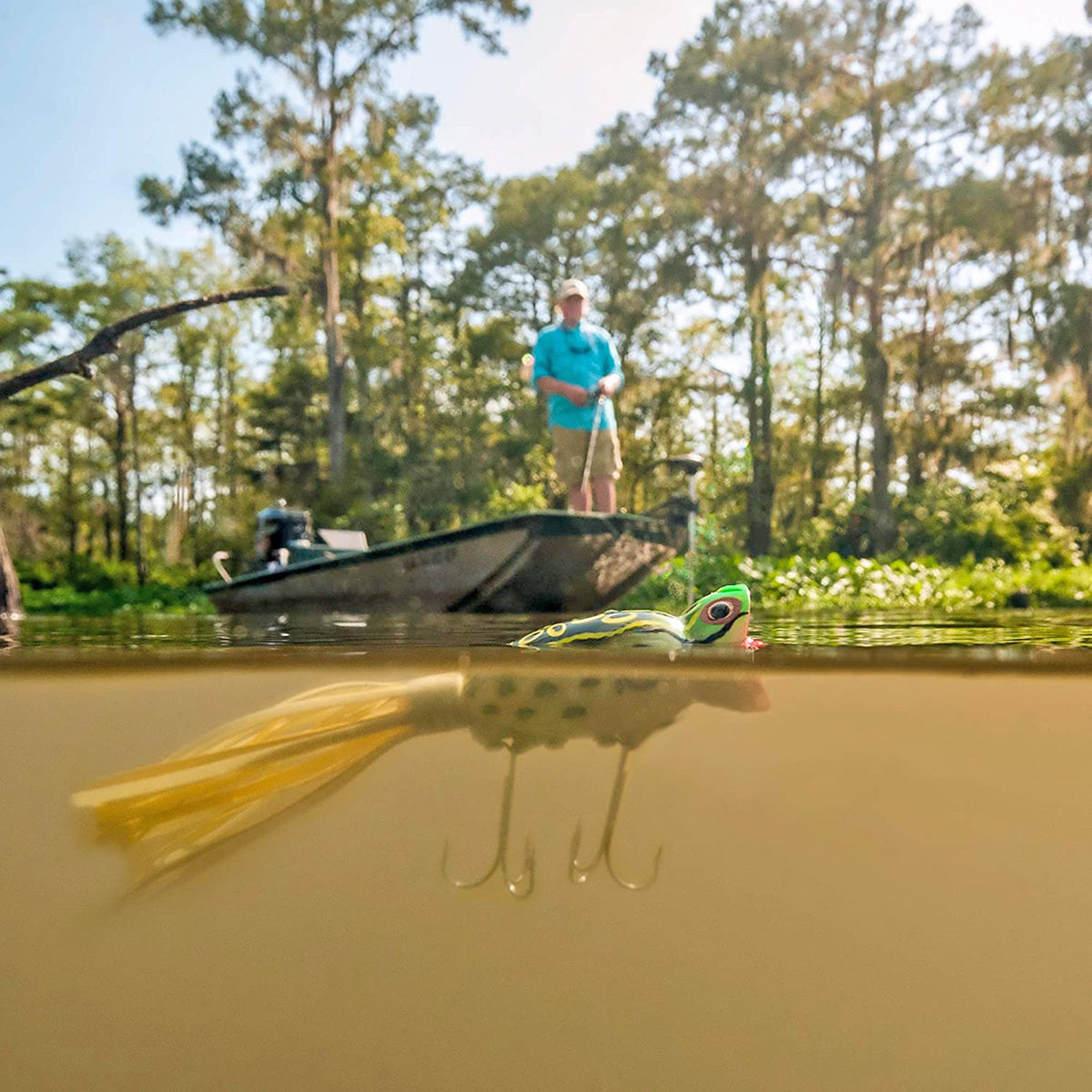 Fishing scene with a boat on water and a person standing on the bank, surrounded by trees. - Forse Sports