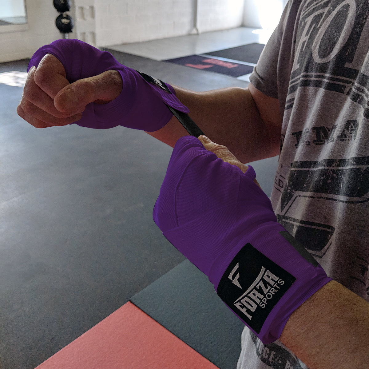 Person wrapping their wrist with purple boxing tape featuring a brand logo.