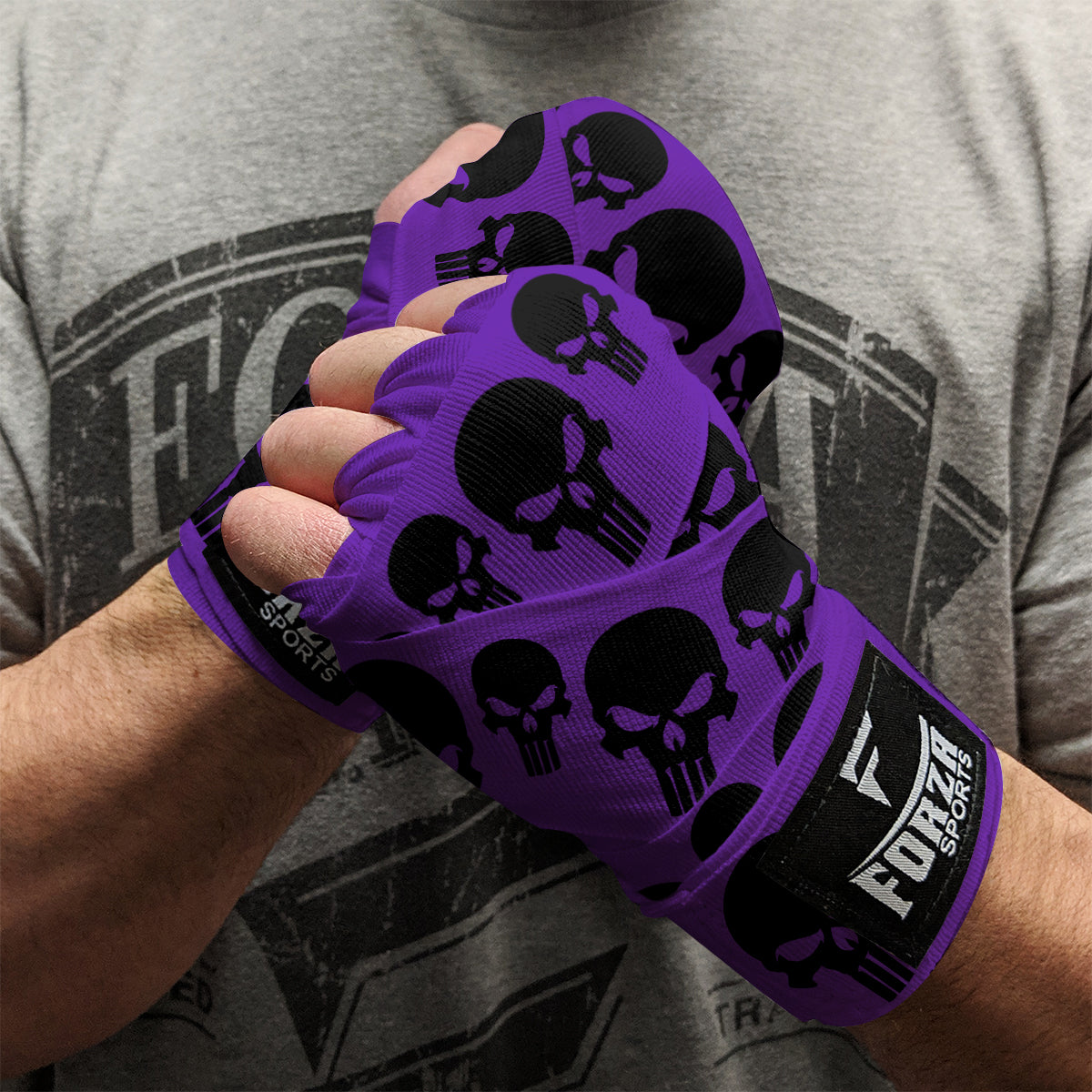 Purple wrist wraps with black skull patterns worn by a person, with a gray t-shirt in the background.