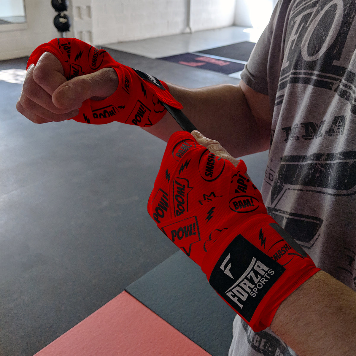 Person wearing red boxing wraps with 'Forza Sports' branding in a gym setting.