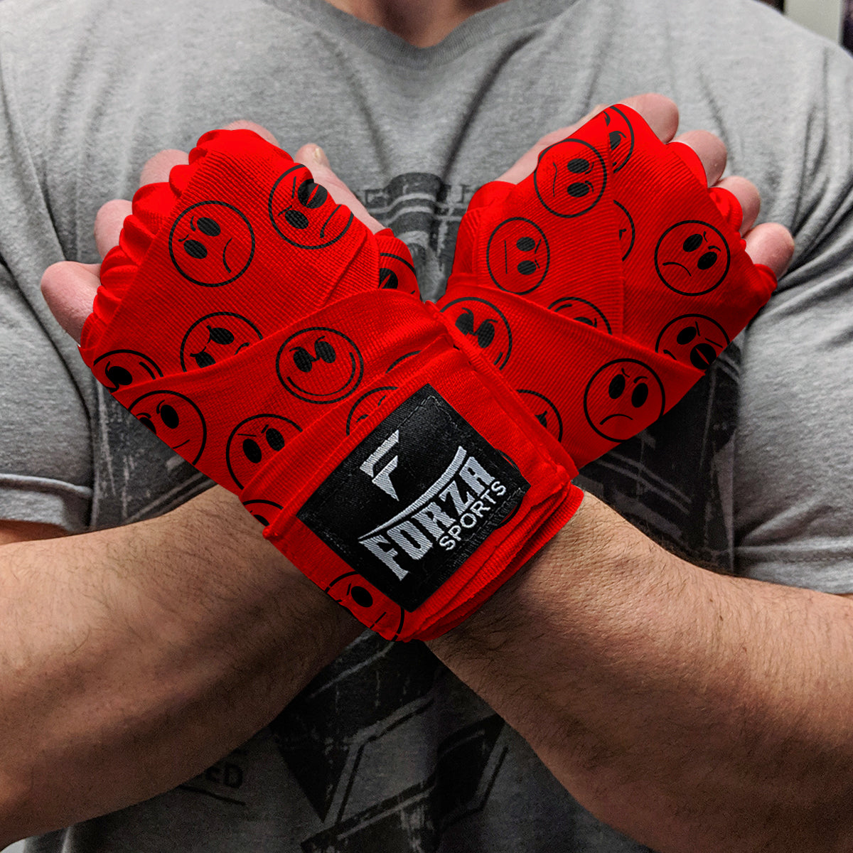 Red wrist wraps with black logos on a person wearing a gray shirt.
