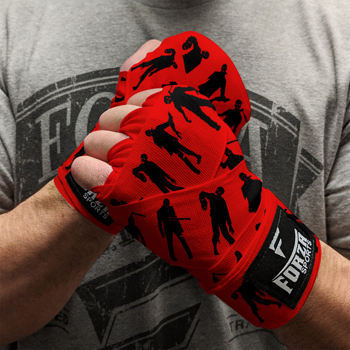 Red boxing hand wraps with black silhouettes on a person wearing a gray t-shirt.