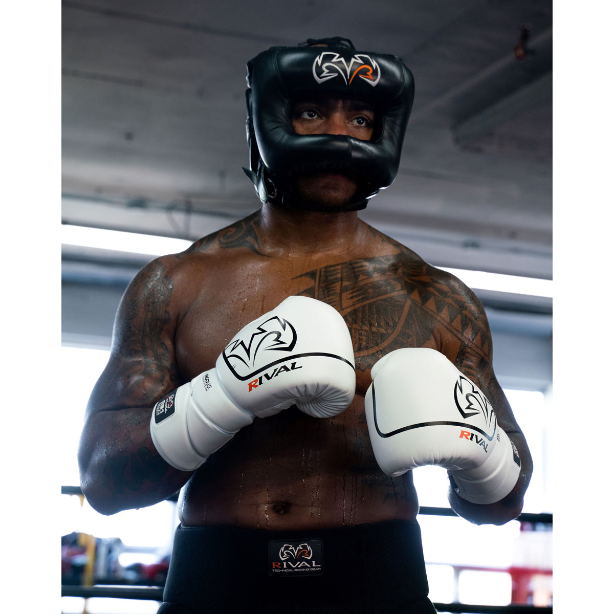 Boxer wearing a black headgear and white boxing gloves in a boxing ring.