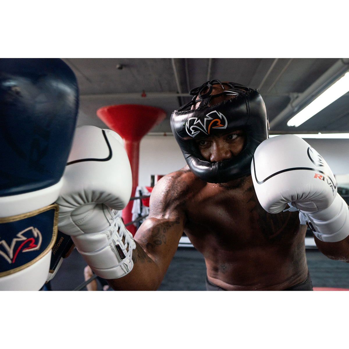 Boxer in training wearing a helmet and gloves in a gym setting