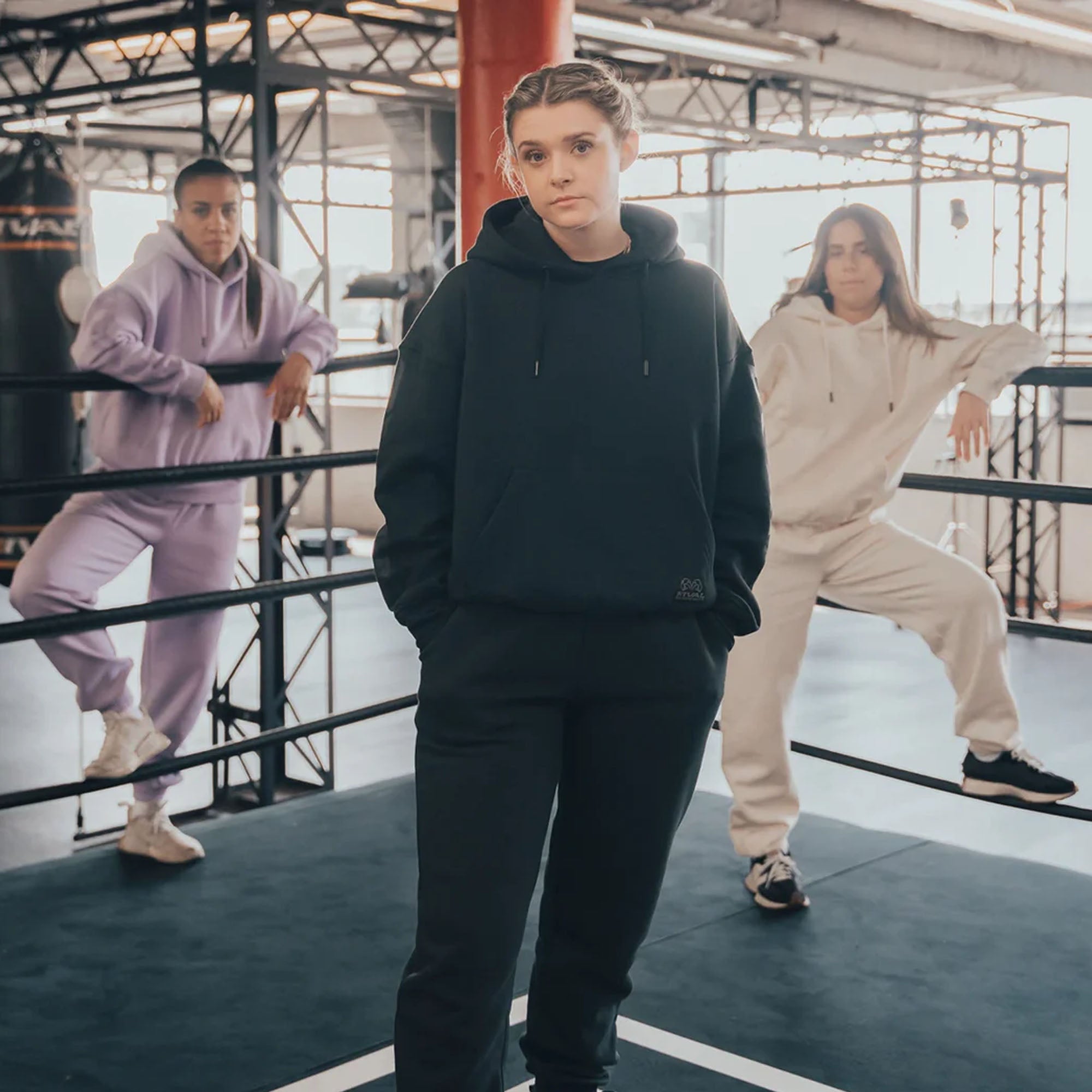 Three people in casual outfits with heavyweight fleece hoodie standing in a modern indoor setting.
