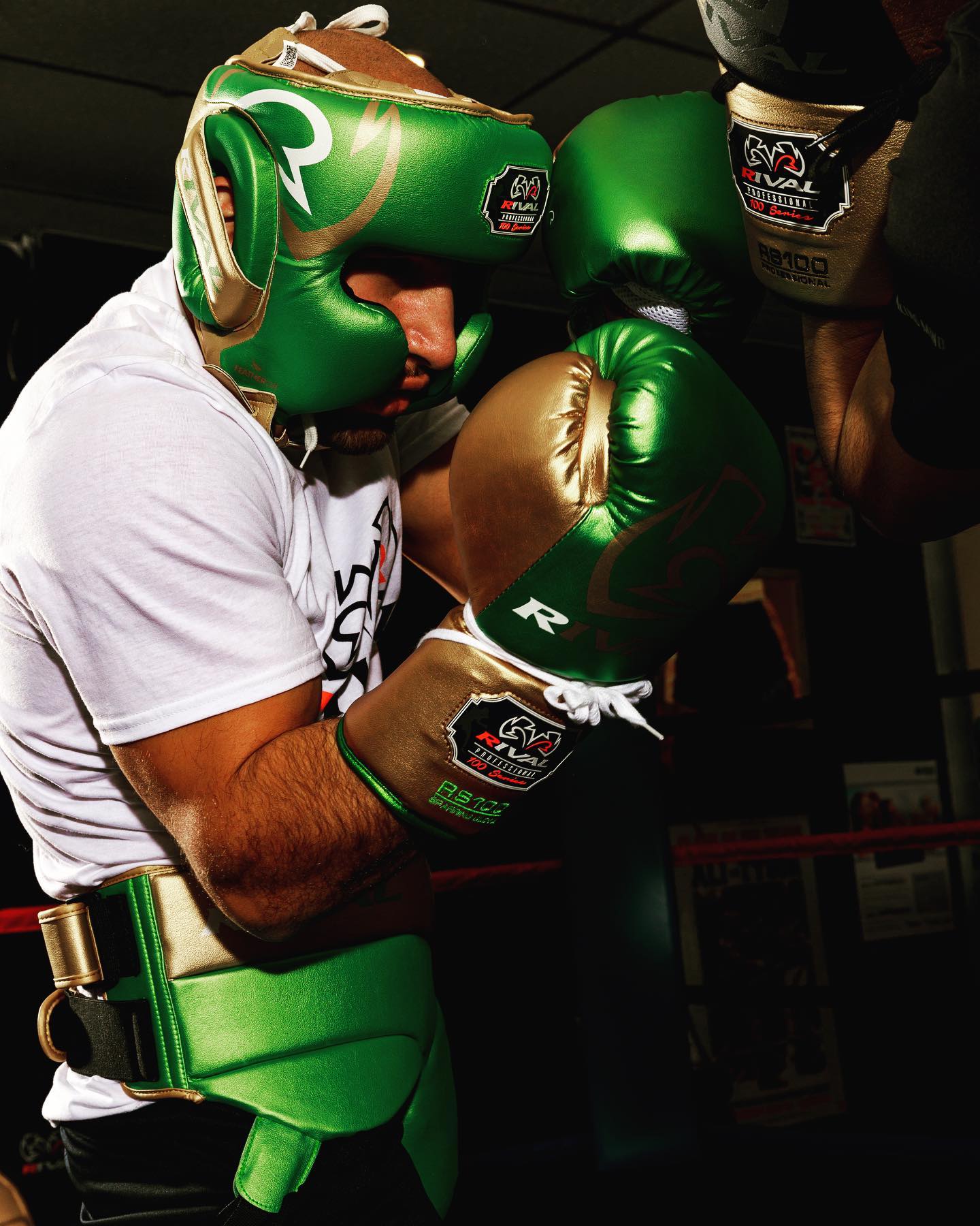 Person wearing green boxing gloves and headgear in a boxing ring.