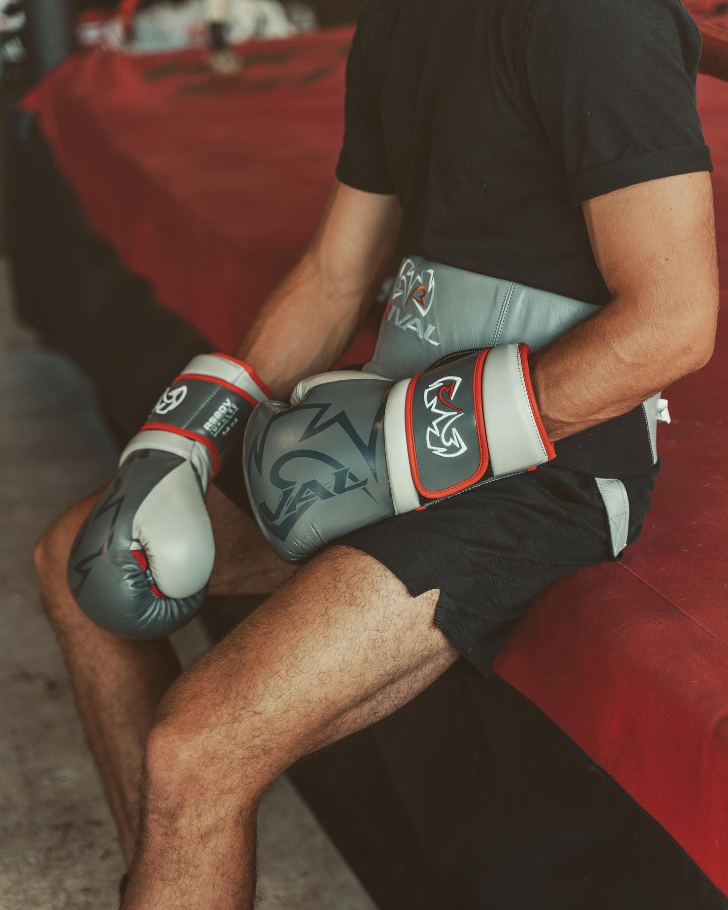 Person wearing boxing gloves sitting on a red couch.