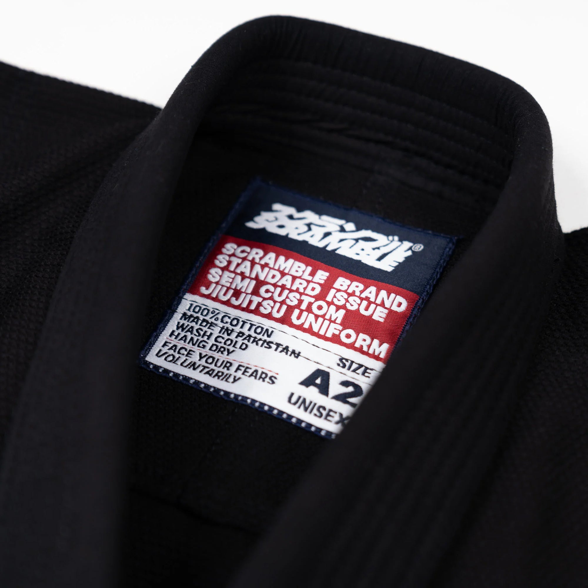Close-up of a Scramble branded jiu-jitsu uniform label on a black gi.