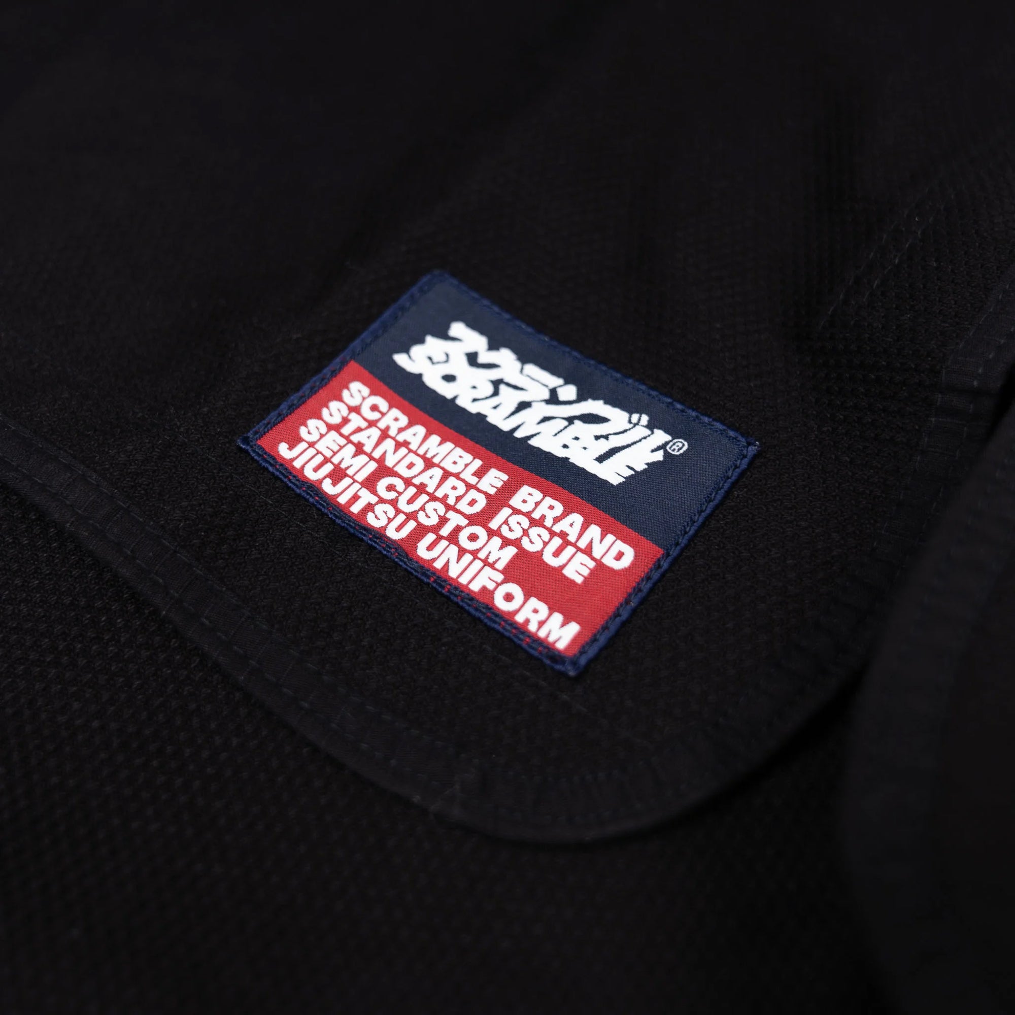 Close-up of a patch on a black uniform with text and branding.