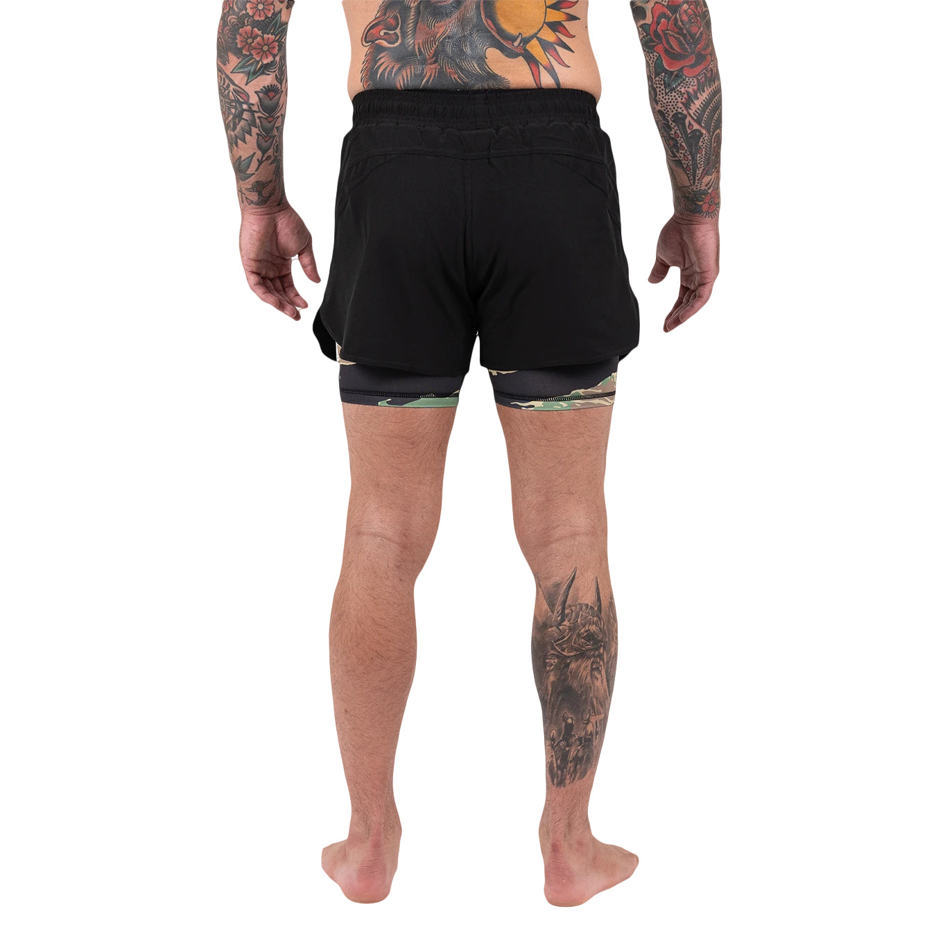 Person wearing black athletic shorts with tattoos on arms and legs against a white background