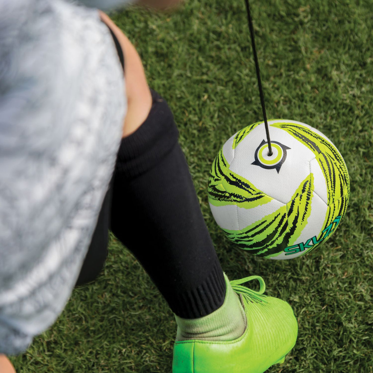 Person practicing soccer star kick touch trainer with a ball on a grass field