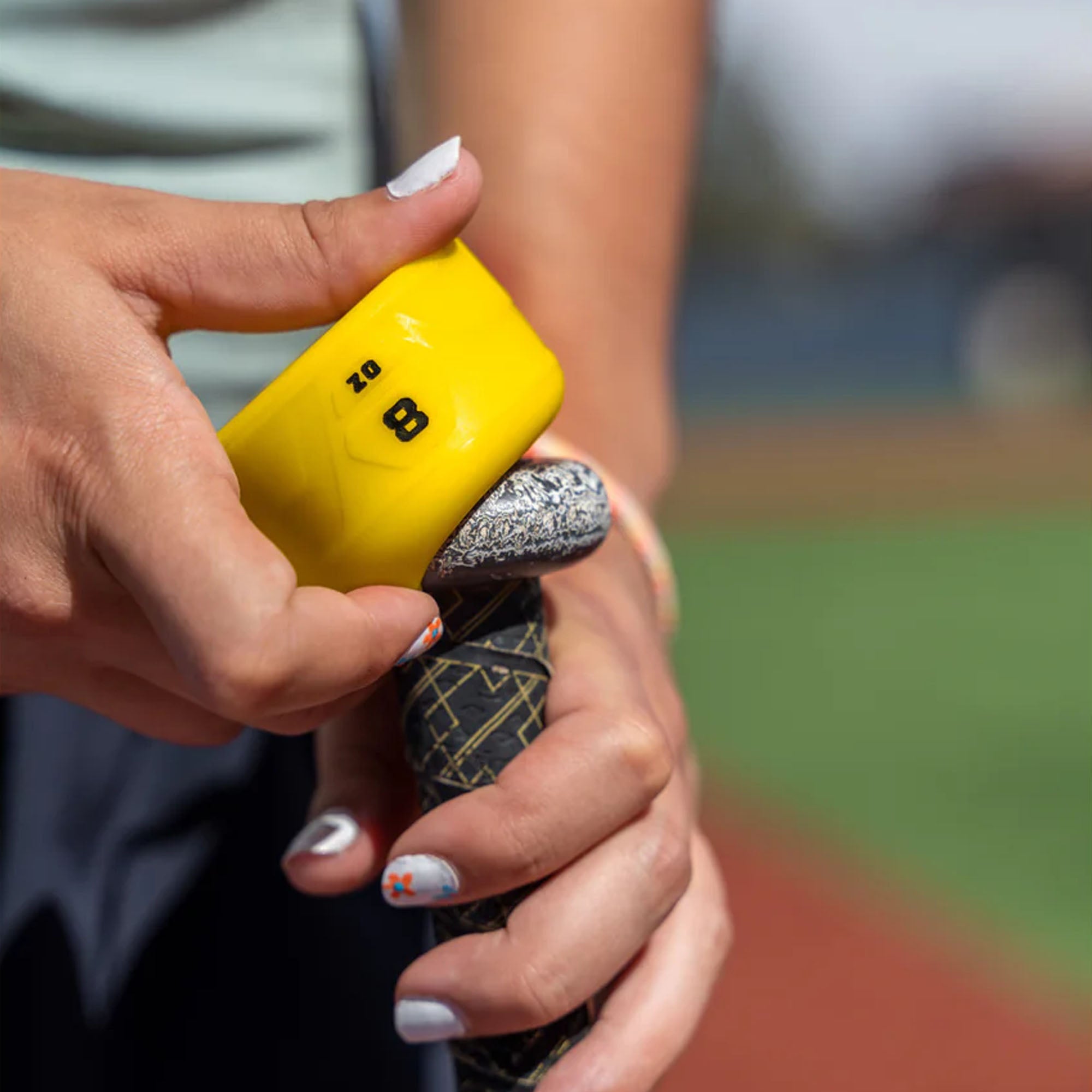 Close-up of hands holding a yellow and black weighted swing knob with a blurred background