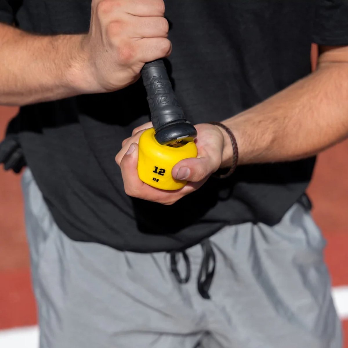 Person holding a yellow and black weighted swing knob with a number on it.