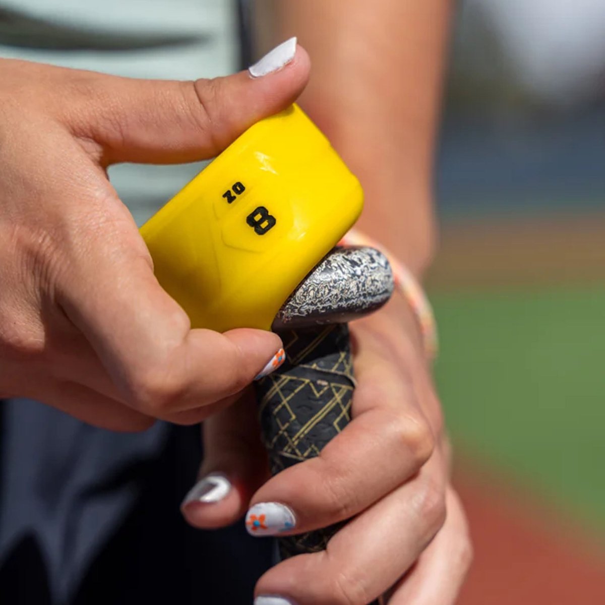 Person holding a yellow and black weighted swing knob with a blurred background