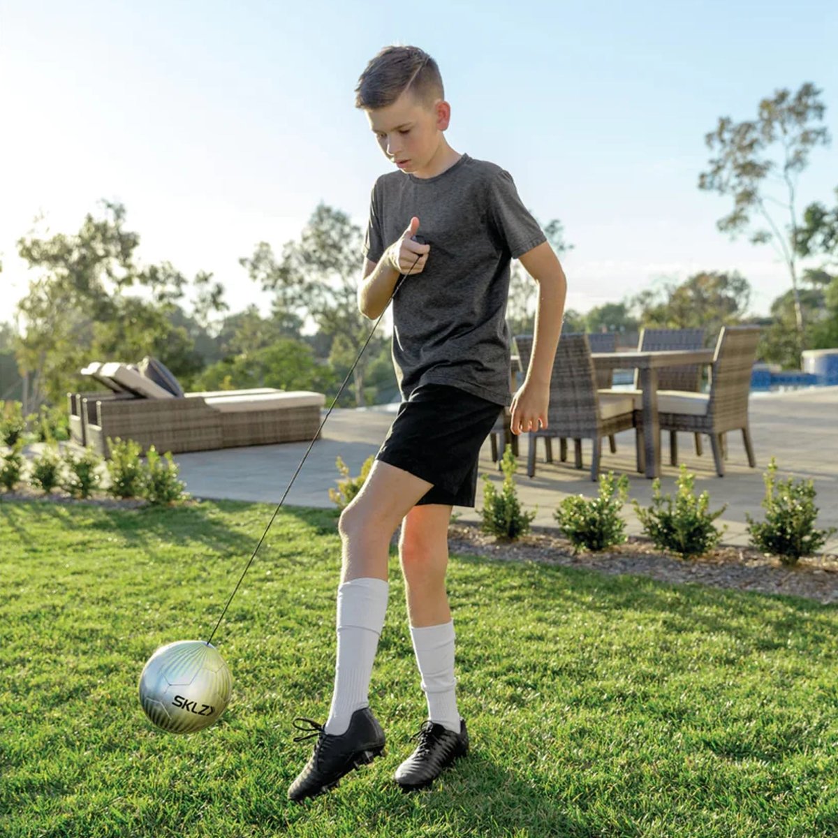 Child playing with a soccer star kick touch trainer ball on grass