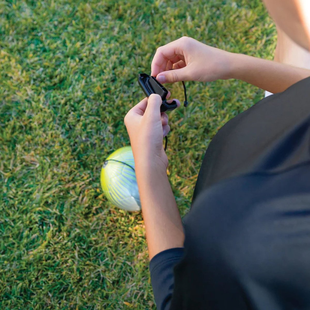 Person holding star kick touch trainer a small device on grass