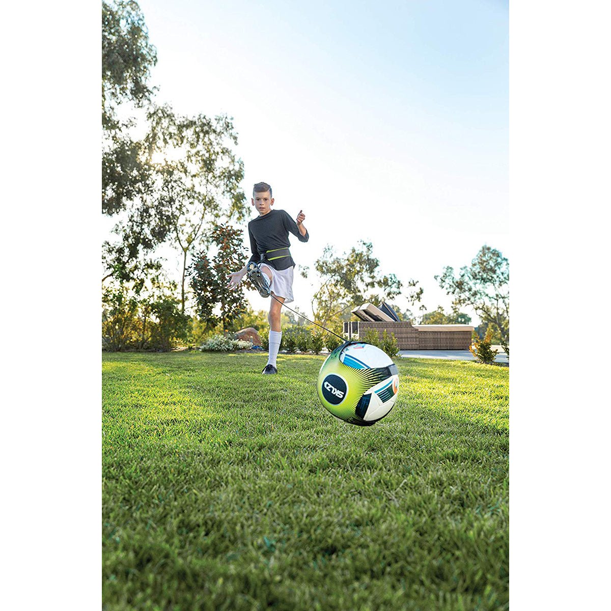 Person playing solo soccer trainer on a grassy field with a clear sky