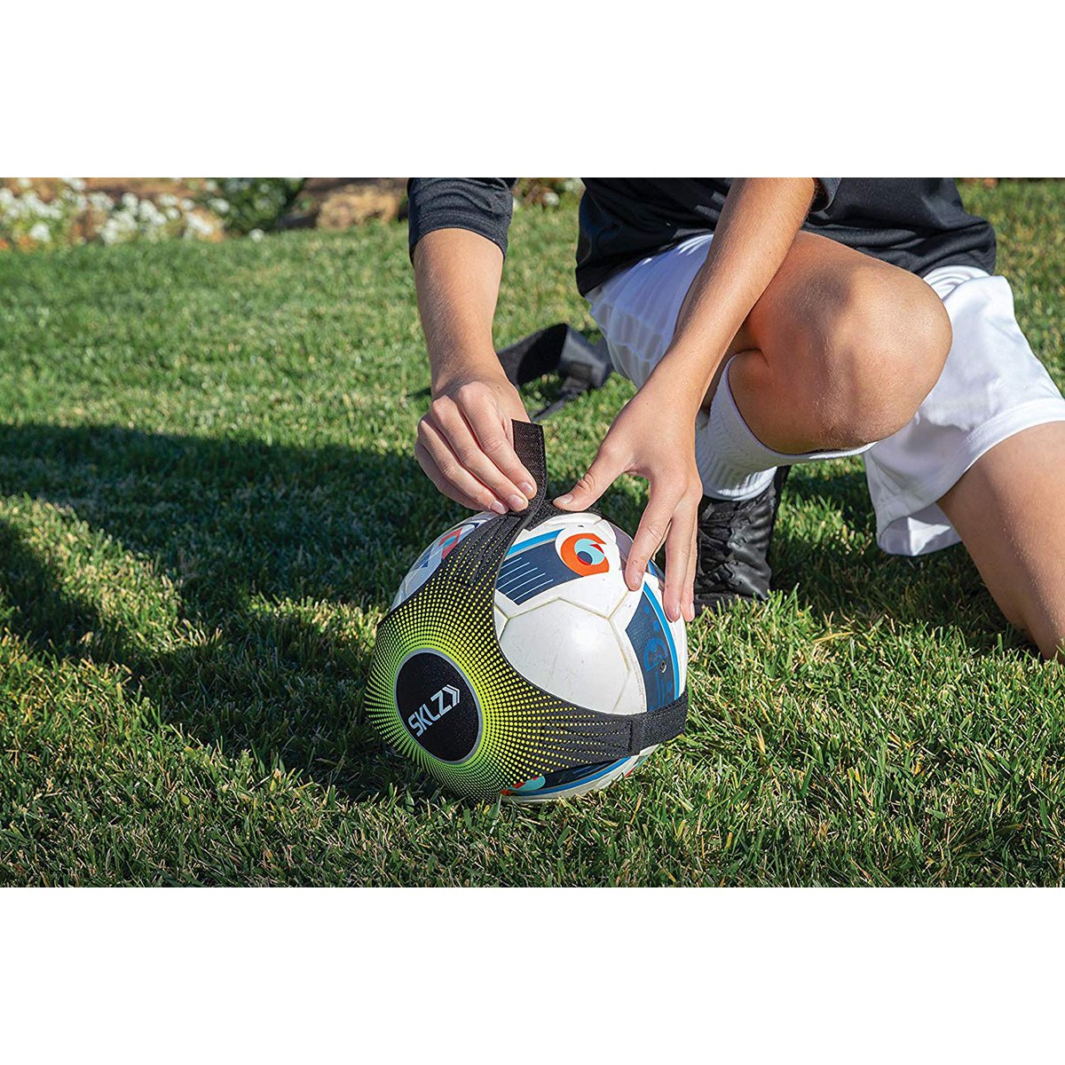 Person adjusting a solo soccer trainer ball on a grassy field