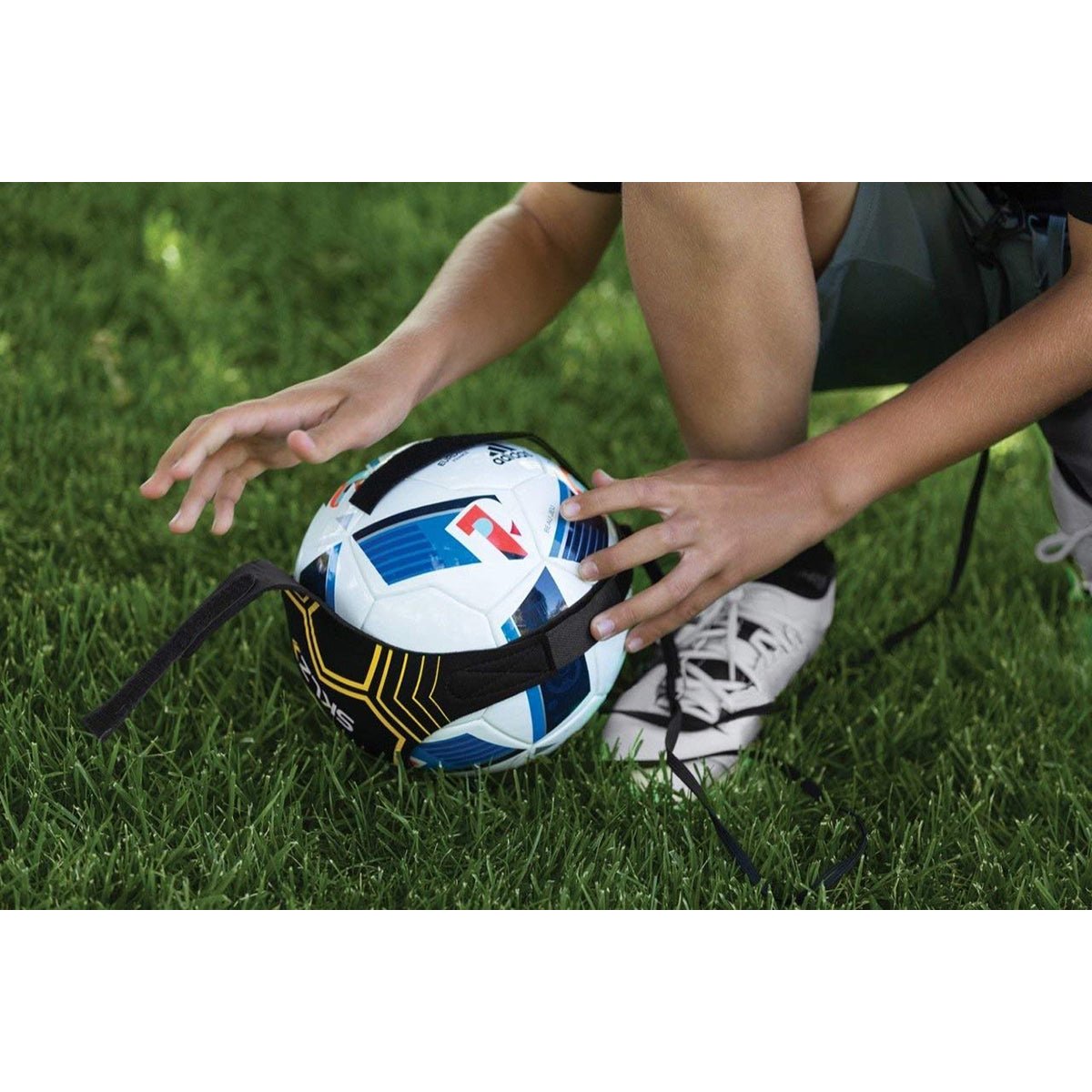 Person holding a solo soccer trainer ball with a visible brand logo on grass