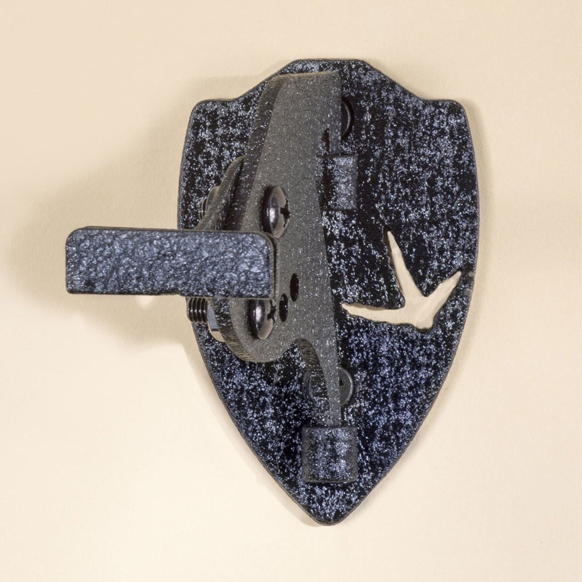 Black metal turkey hooker wall mount with speckled pattern on a beige background